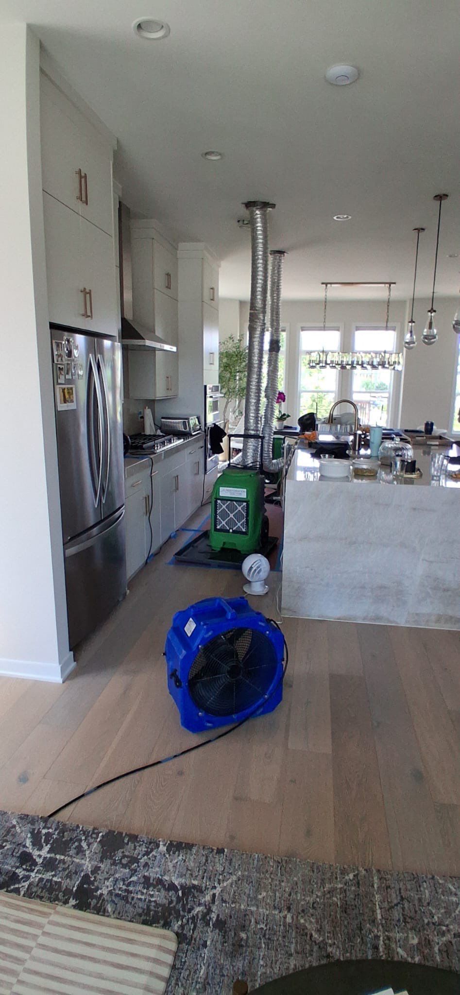 Multiple dehumidifiers operating in sequence to extract residual moisture from contained restoration area.