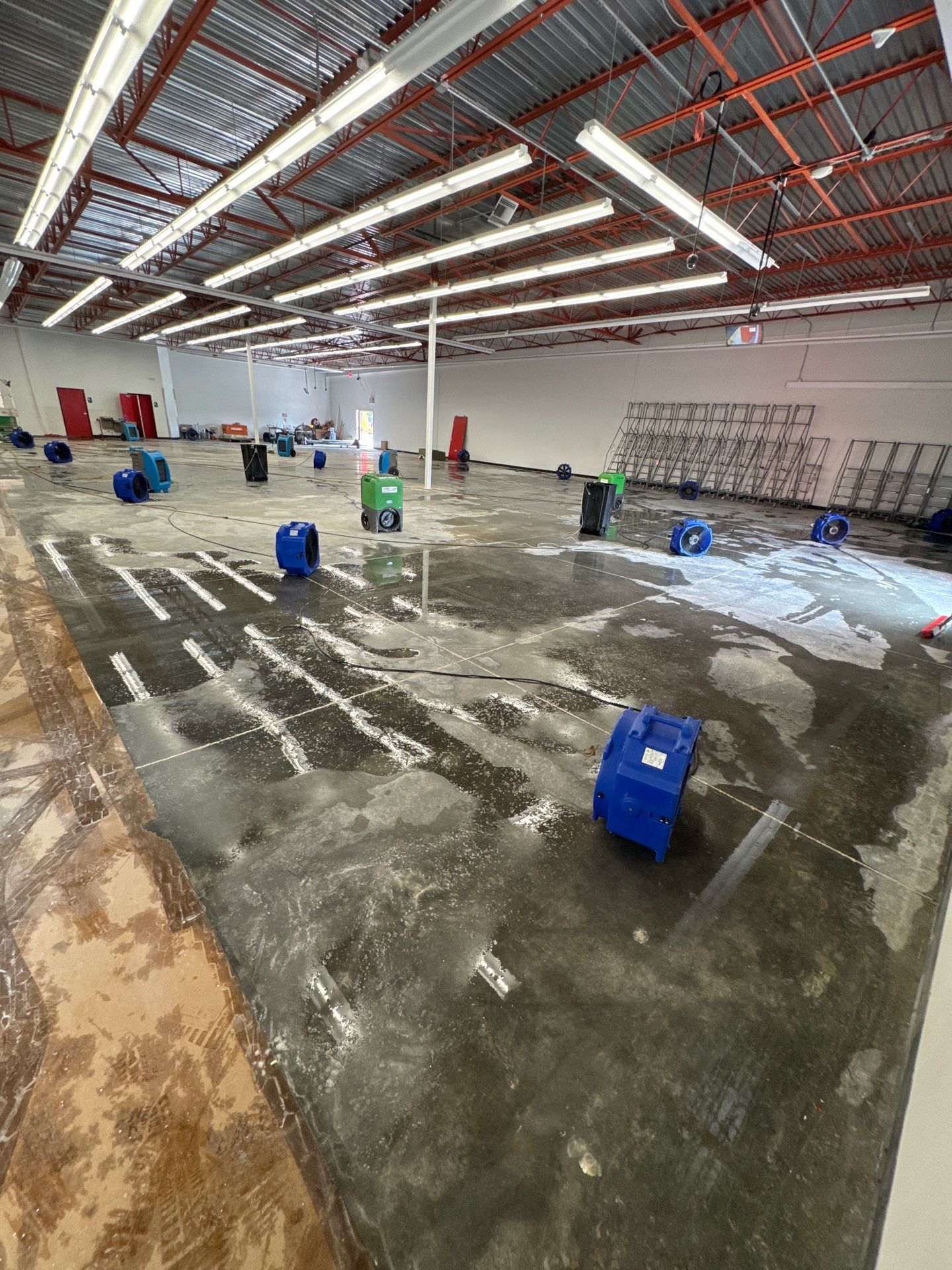 Structural drying phase with dehumidifiers and air movers positioned to dry framing and subfloor after water extraction.