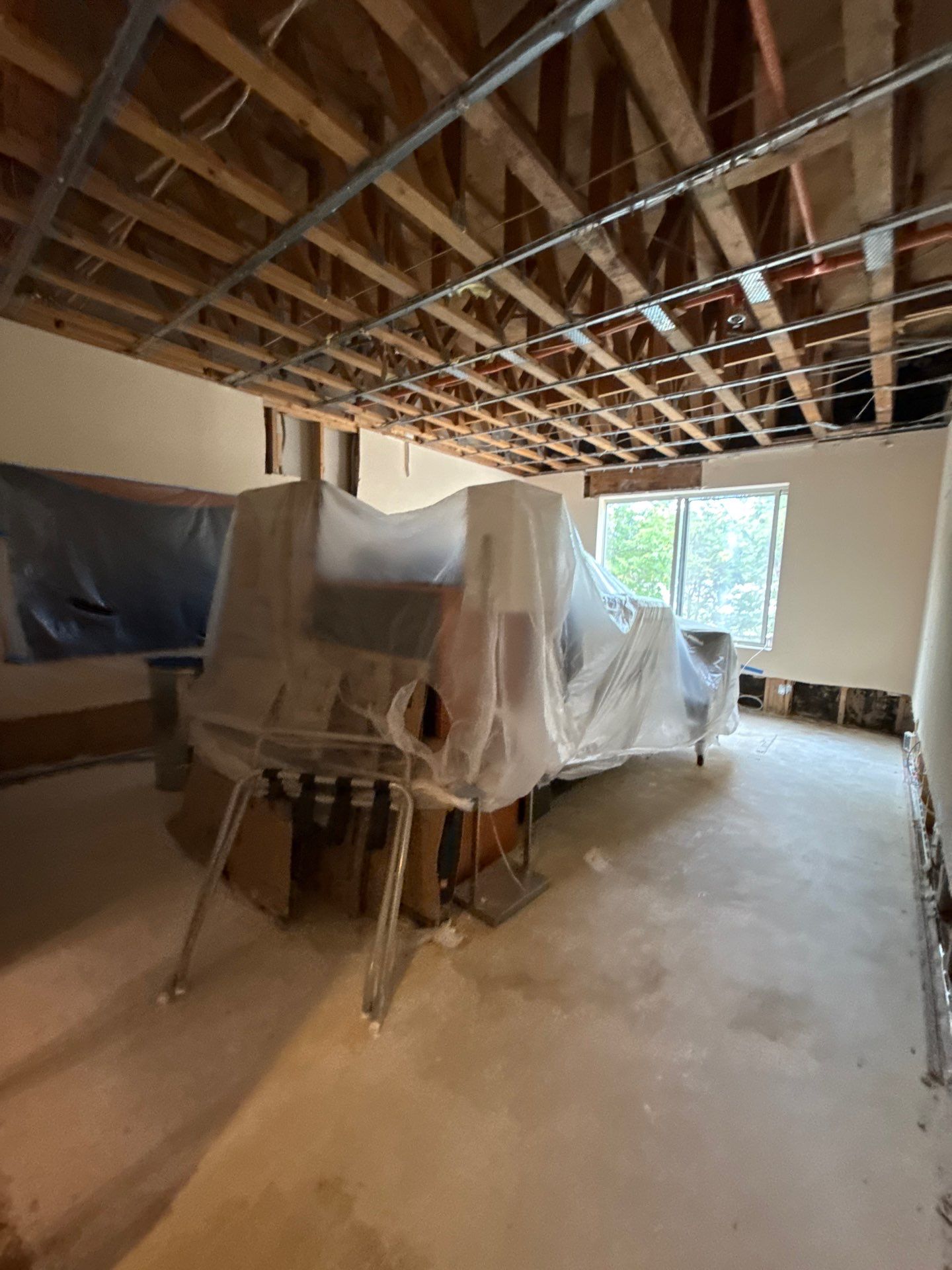 Standing water extraction underway in Manassas water damage restoration, wet flooring and structural materials visible.