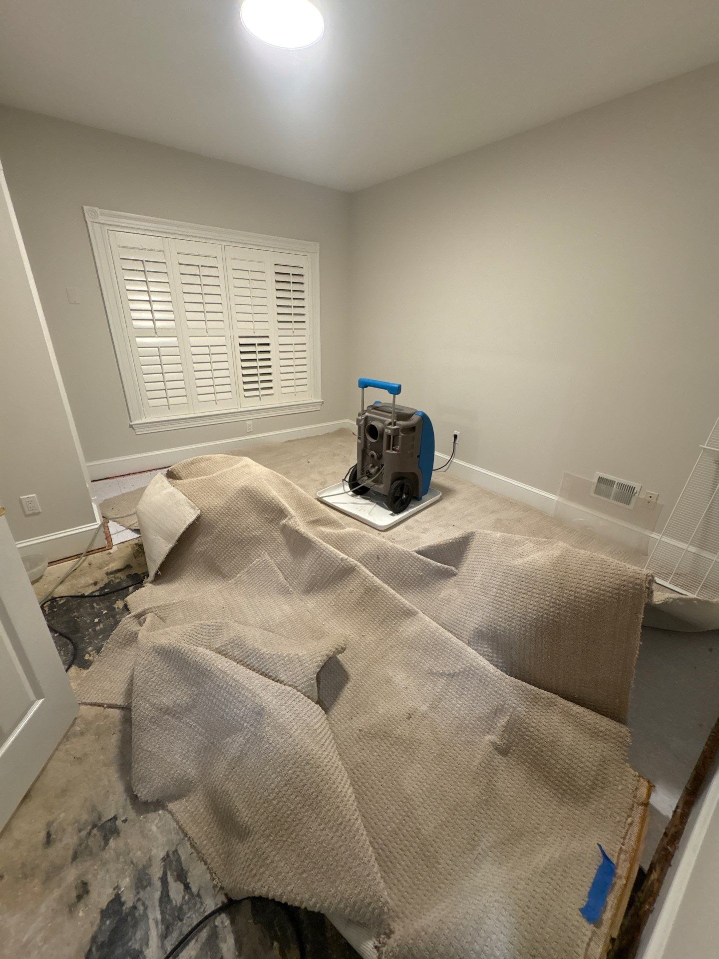 Standing water extraction underway in McLean water damage restoration, wet flooring and structural materials visible.