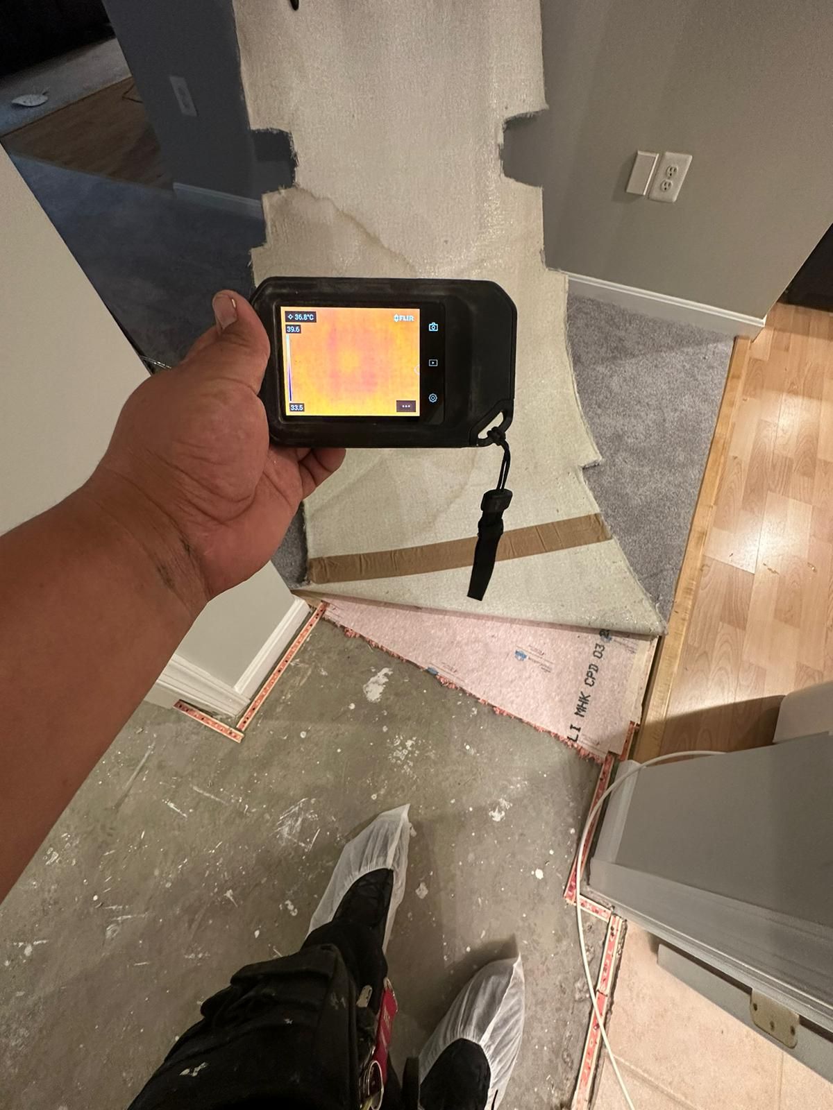 Thermal imaging camera documenting moisture distribution across affected surfaces during drying process.