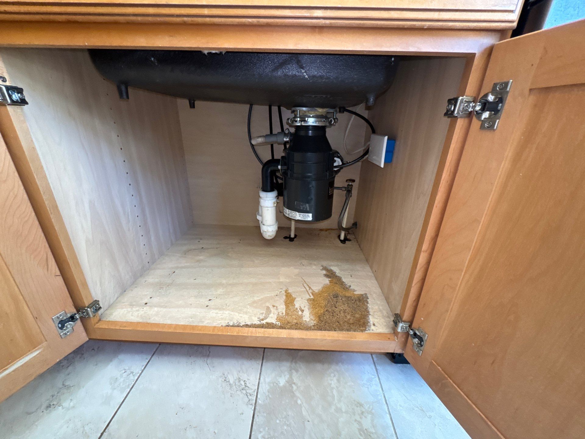 Water pooling beneath a kitchen sink cabinet during initial assessment of water damage in McLean.