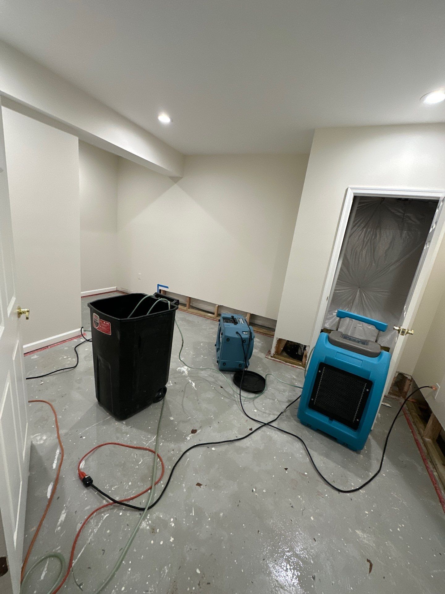 Dehumidification equipment positioned for structural drying of water-affected wall cavity and framing.