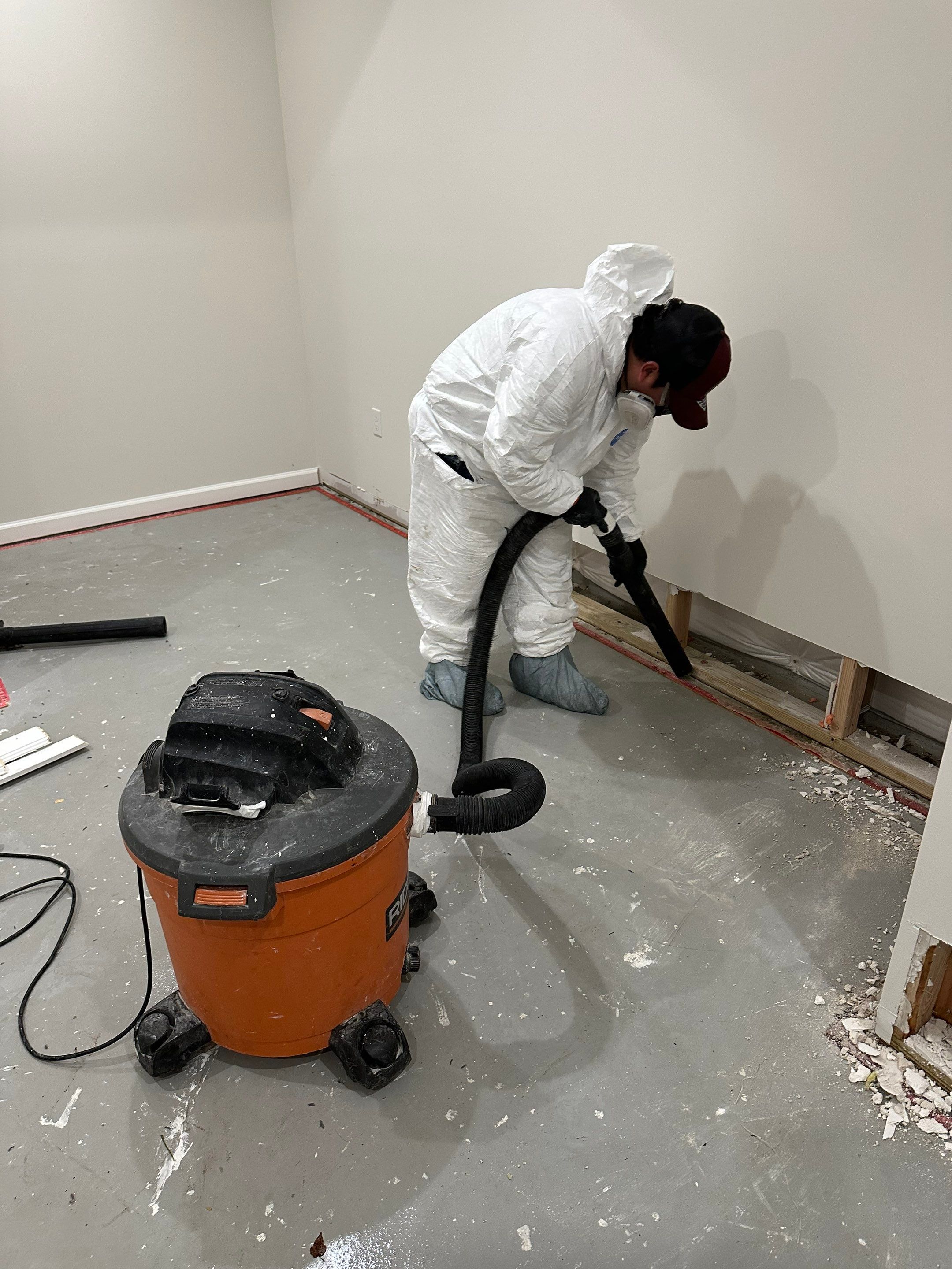 Water-damaged baseboard and wall base in McLean home during initial assessment and dehumidification setup.