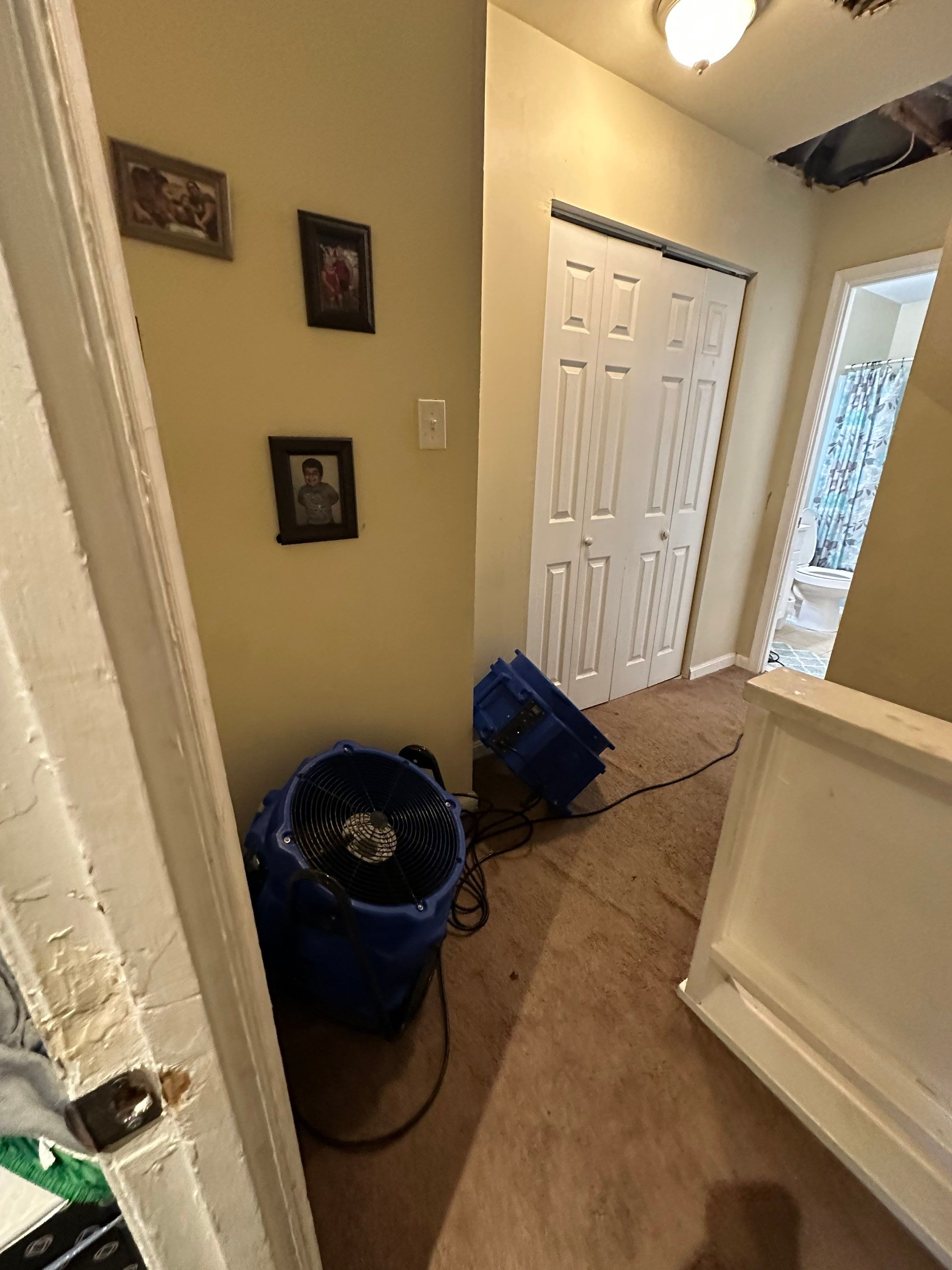 Ceiling damage assessment showing water intrusion extent with drying equipment operating in background.