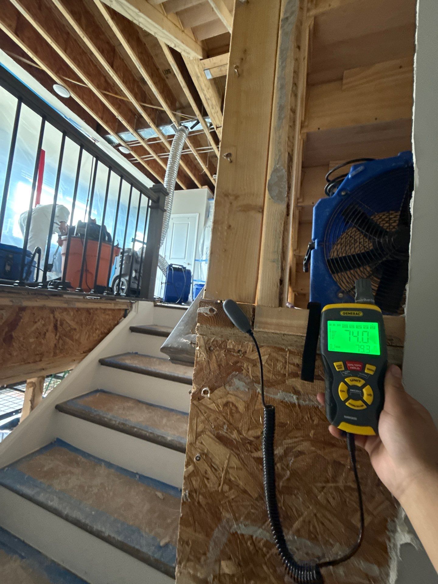 Structural drying equipment positioned to remove moisture from wall cavities and framing.