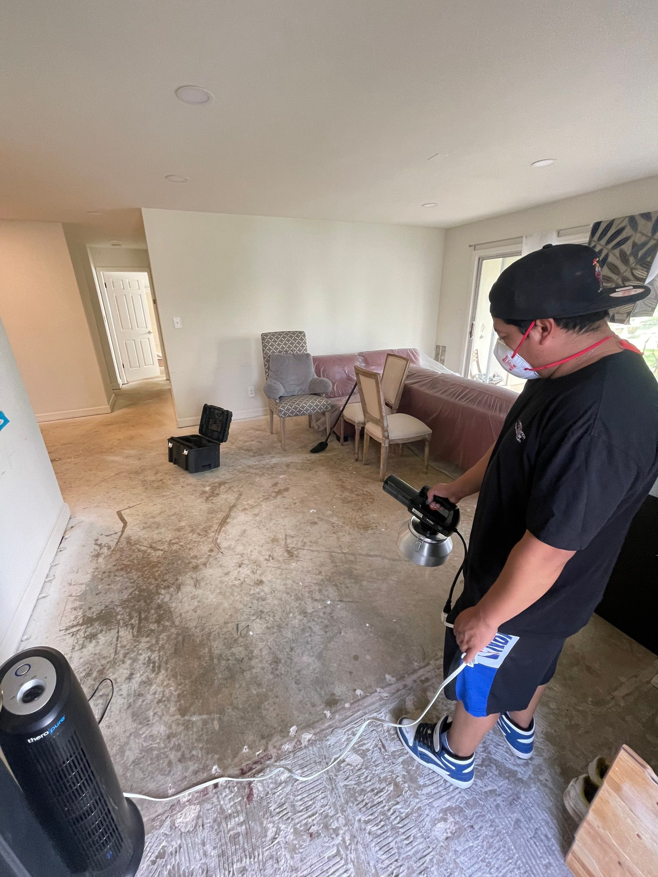 Water damage restoration in Alexandria: dehumidification equipment positioned in affected room during initial drying phase.