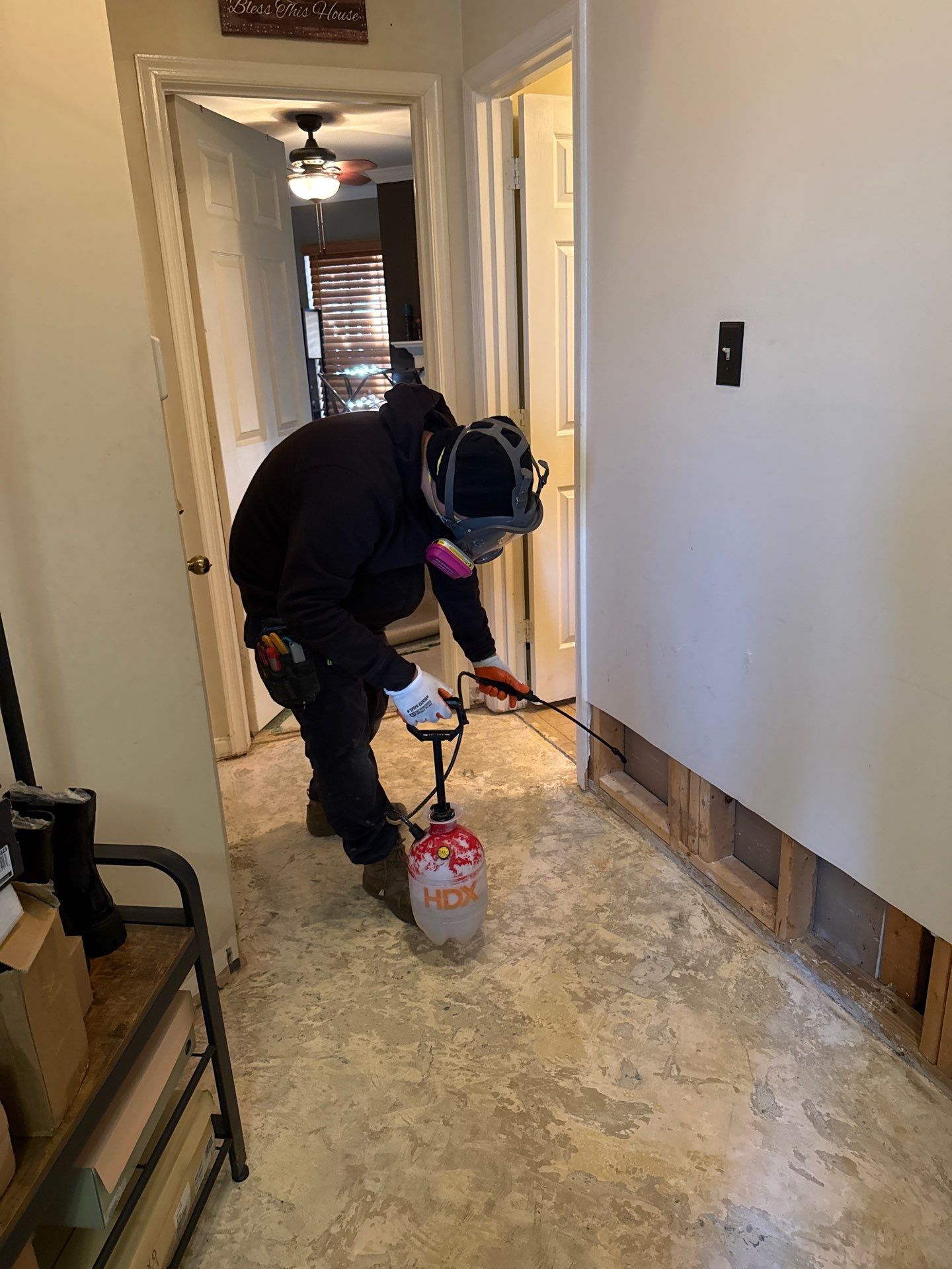 Close-up of moisture-damaged baseboard marked for removal during remediation sequence.