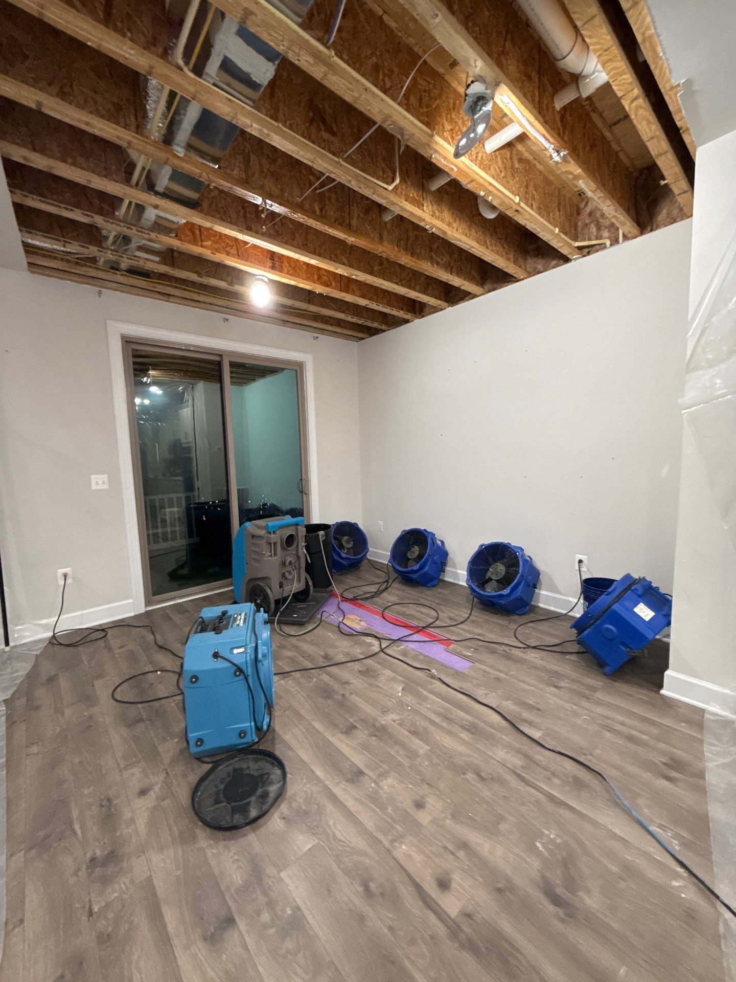 Drying equipment positioned to extract moisture from affected ceiling and subfloor areas.