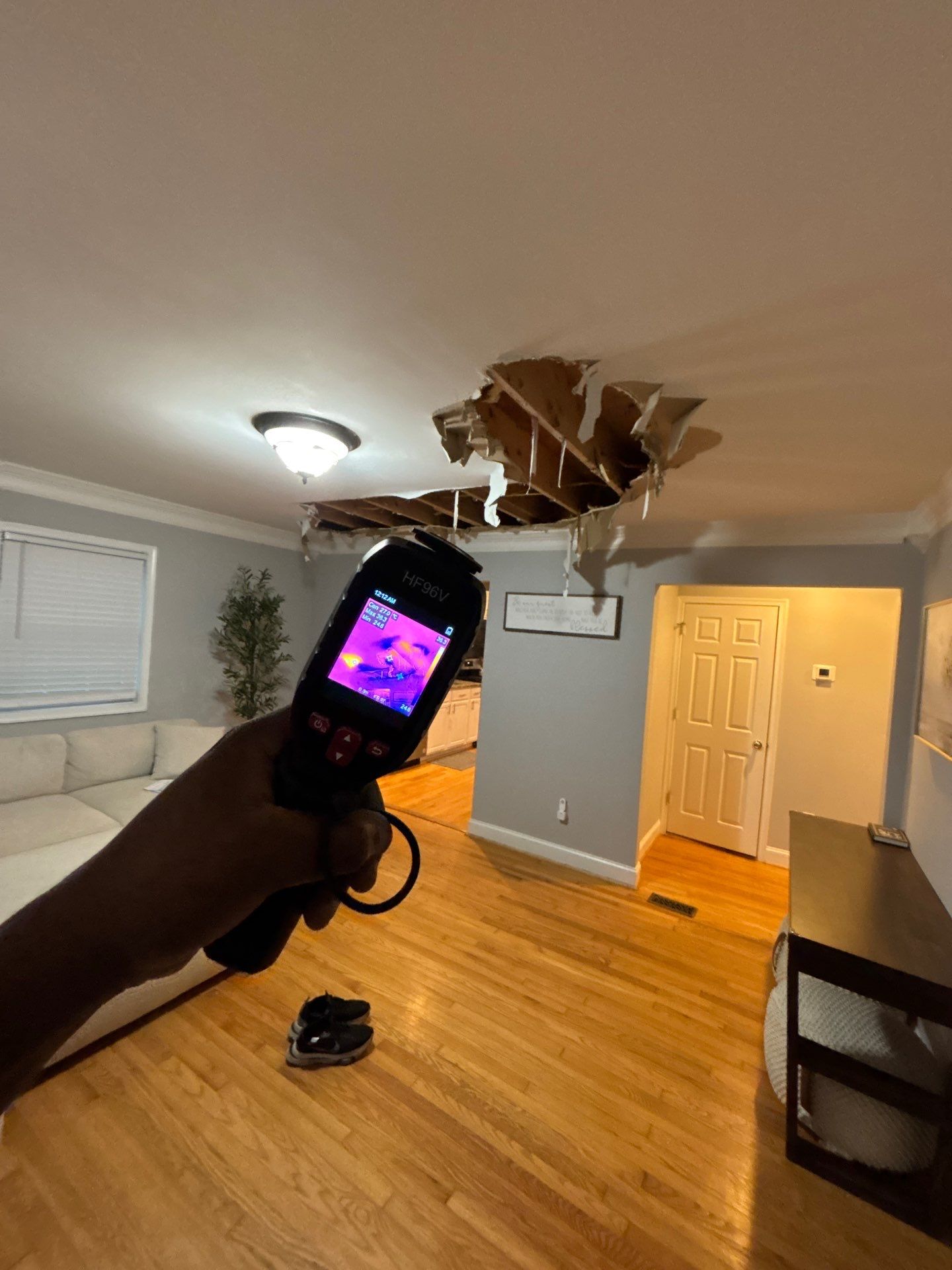 Ceiling section removed to expose framing and assess moisture penetration during water damage restoration.