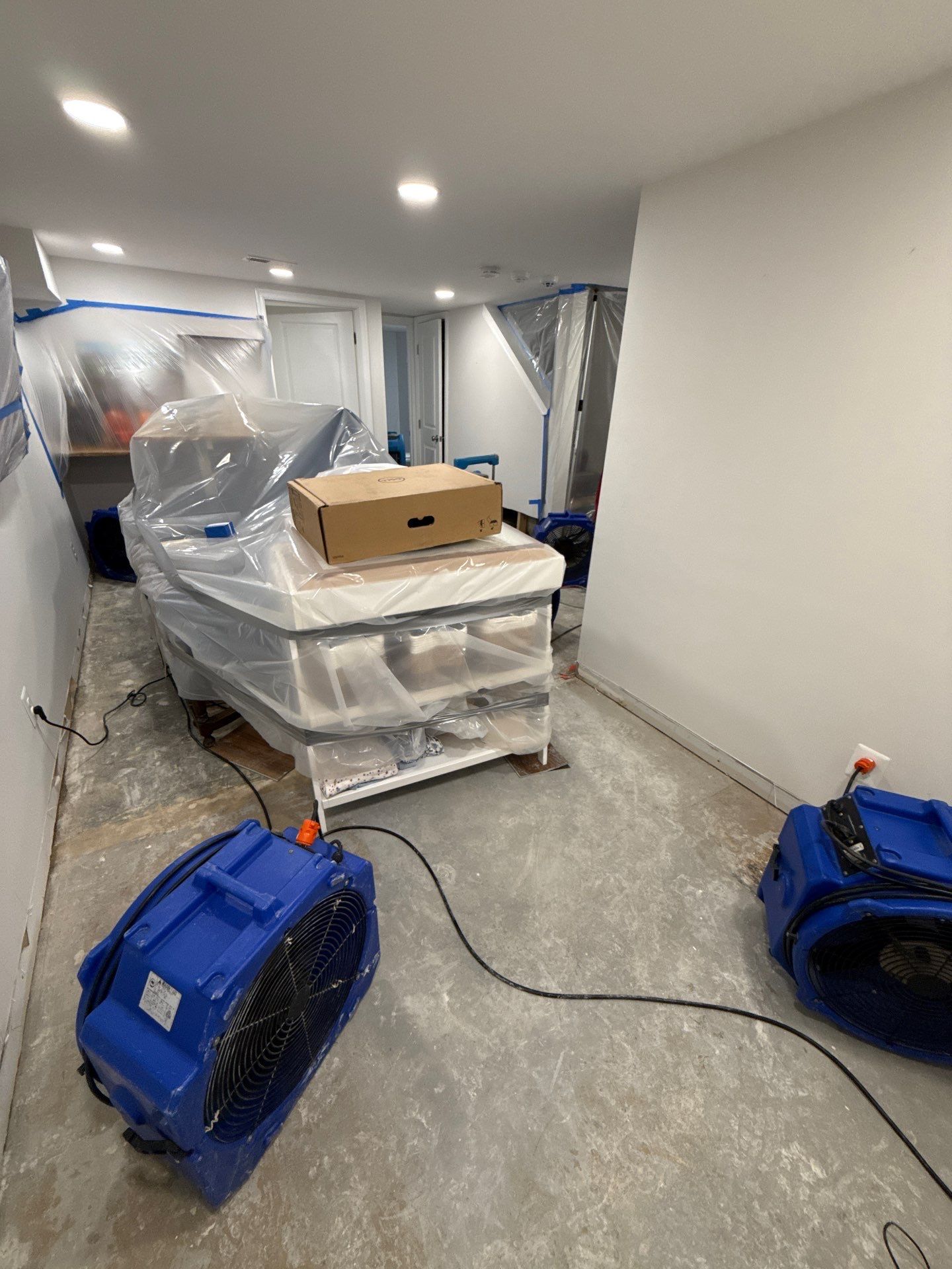 Structural drying phase with dehumidifiers and air movers positioned throughout affected space.