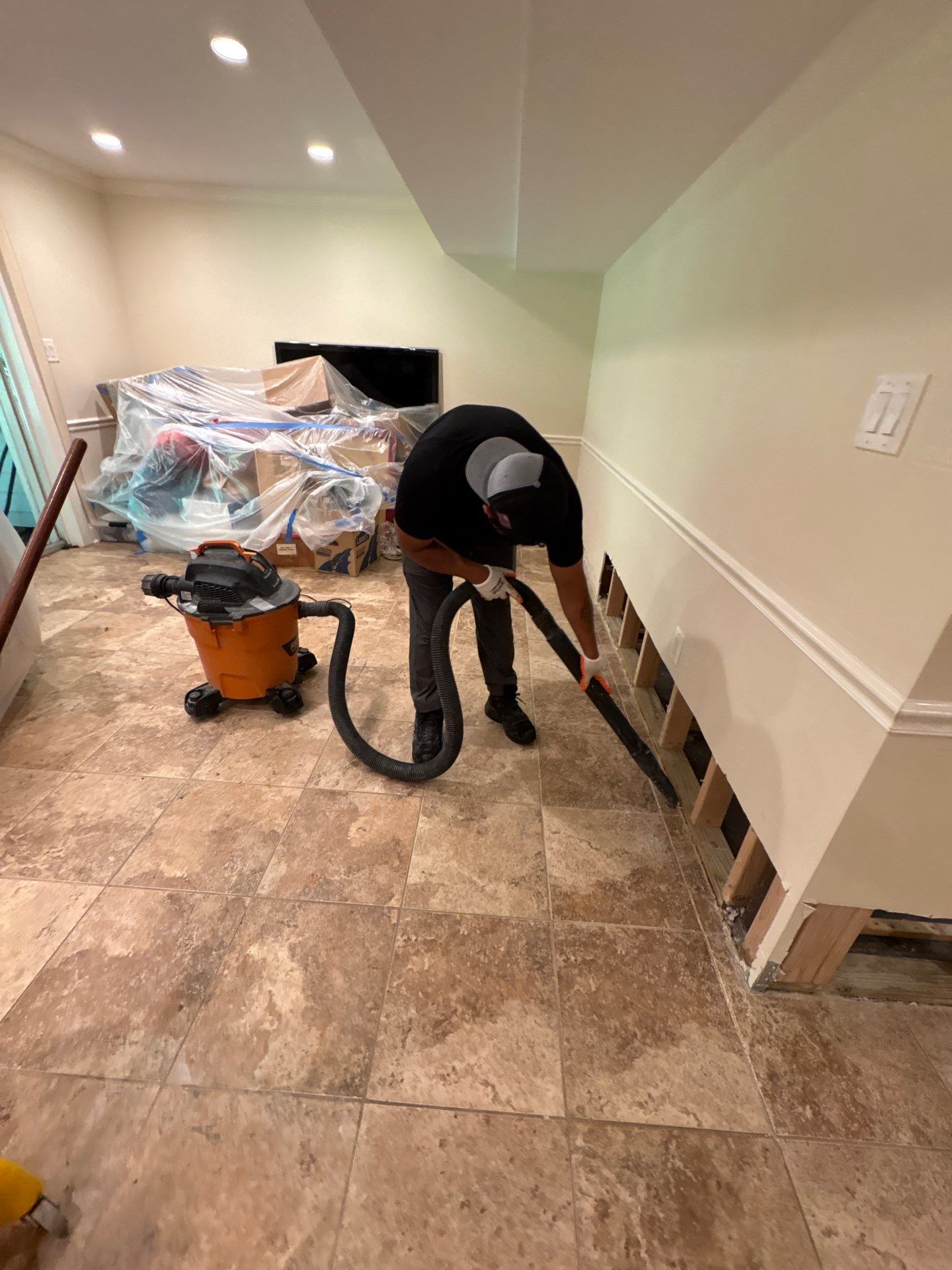 Baseboard removal and preparation for replacement, exposing wall cavities for thorough drying before reinstallation.