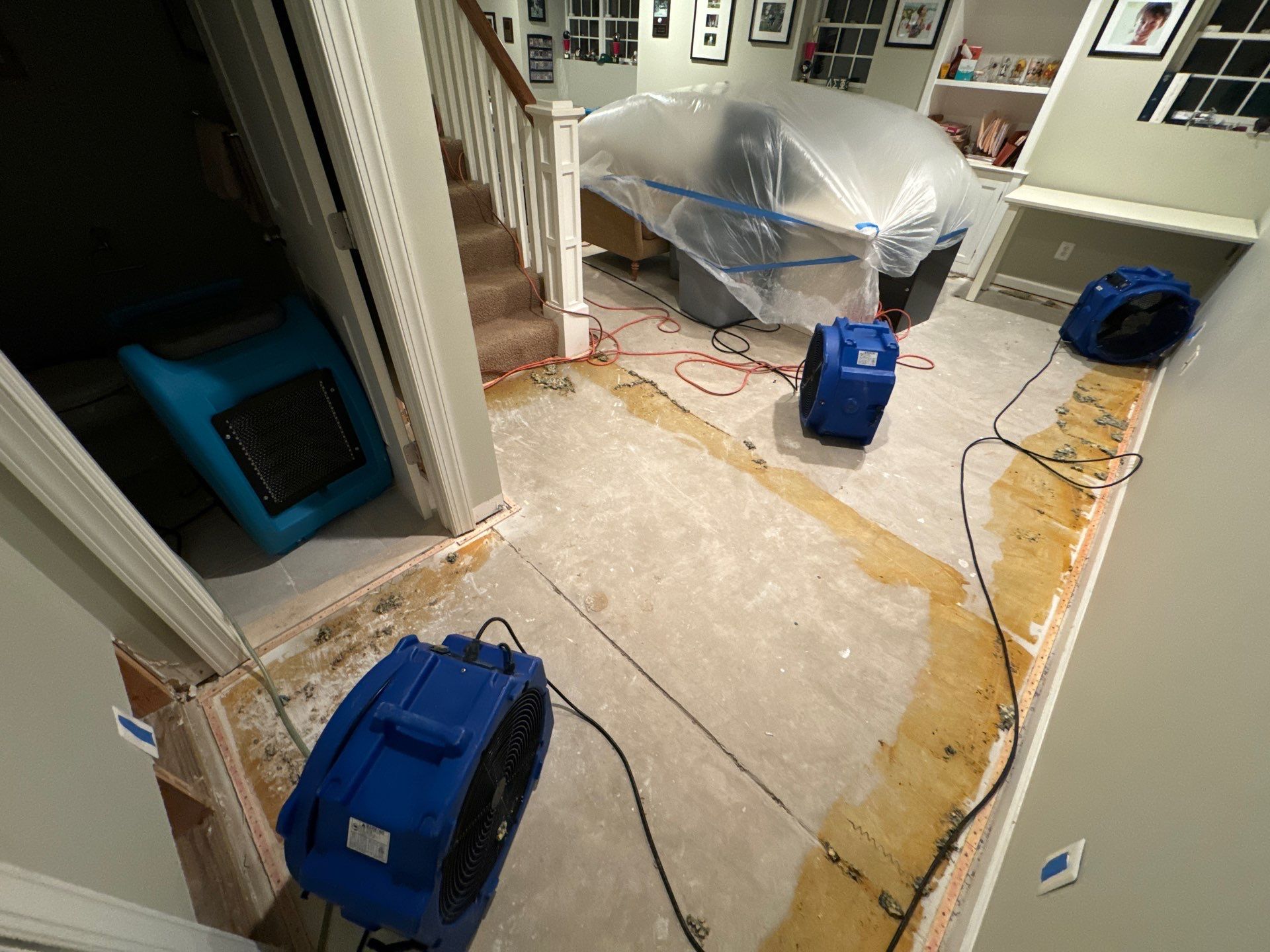 Final-stage water damage restoration in Alexandria with flooring remediation complete and equipment removal underway.