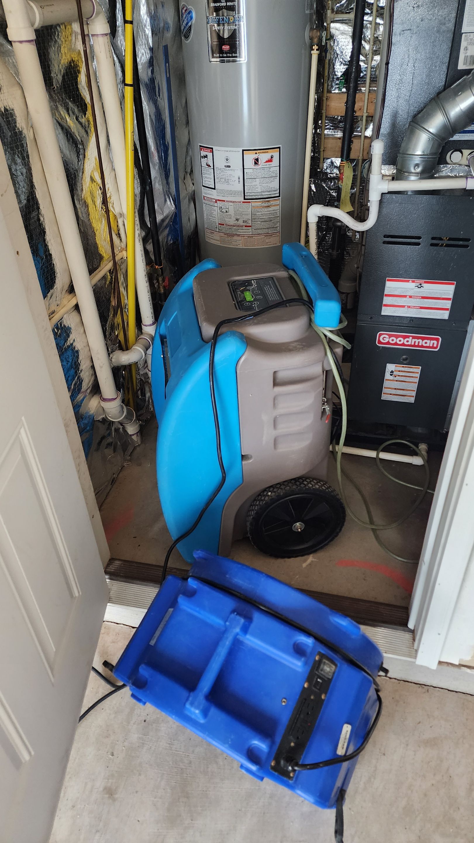 Mid-stage drying setup showing dehumidifiers and air movers extracting moisture from affected flooring.
