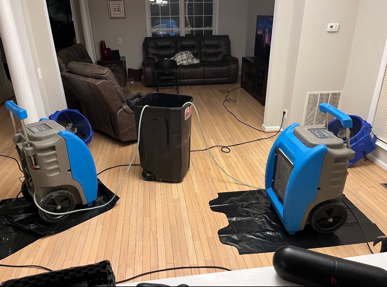 Structural drying in progress with dehumidifiers and air movers positioned throughout affected areas.