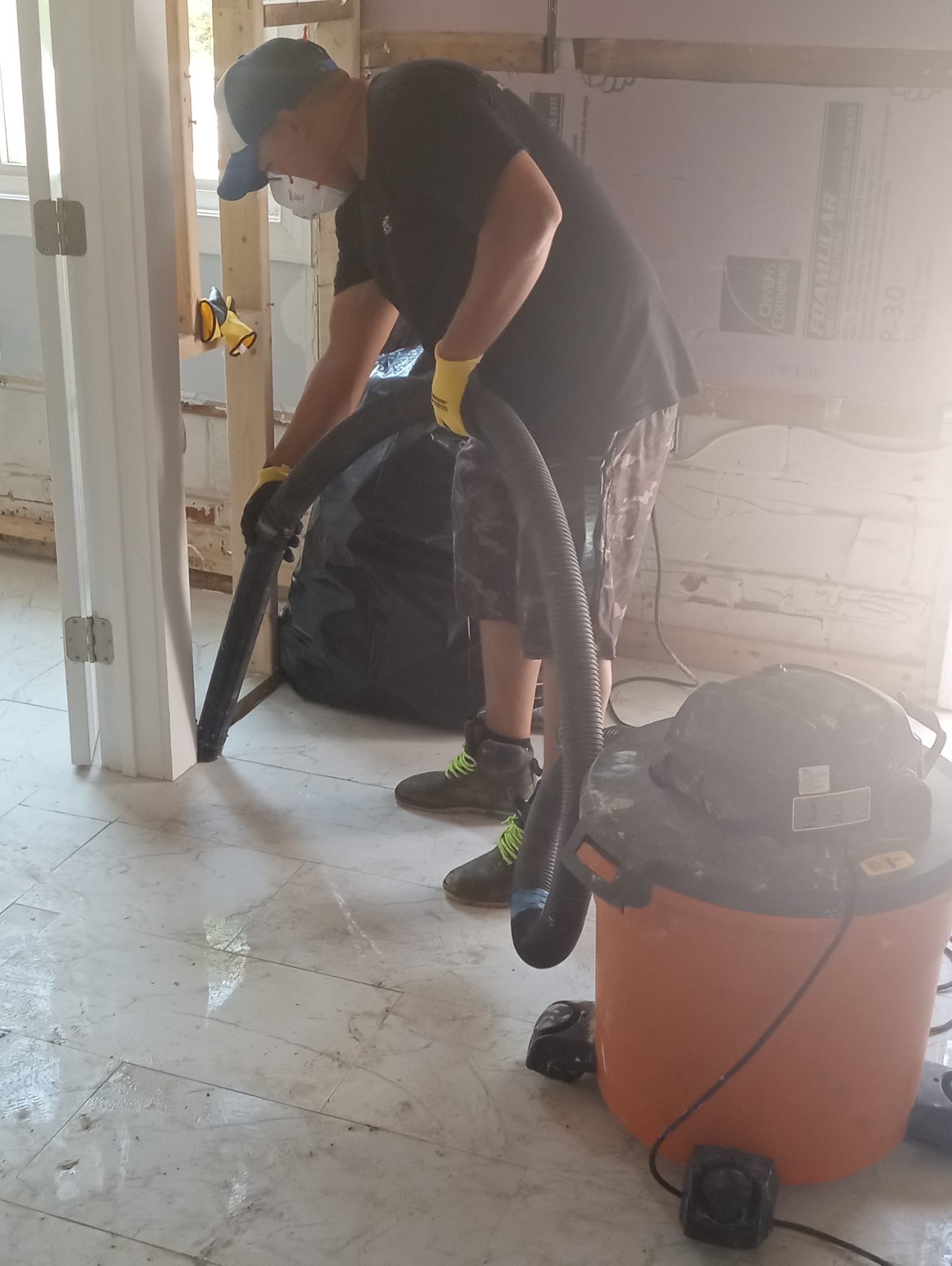 Dehumidifier and air movers positioned for structural drying in water-damaged room.