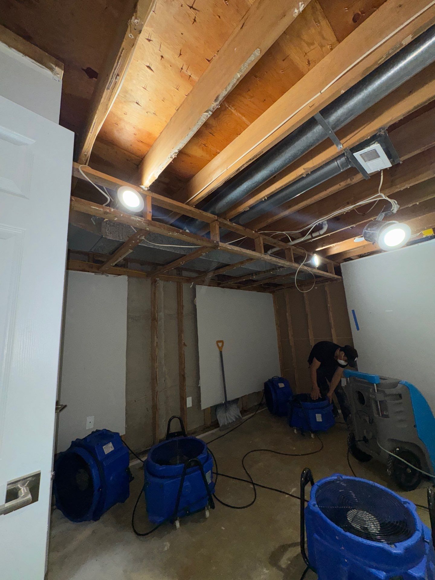 Water damage restoration in Fairfax: drying equipment positioned near wet ceiling and structural framing during initial assessment.