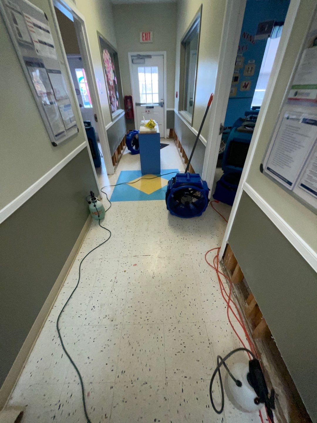 Mid-stage drying setup showing dehumidifiers and air movers managing moisture during water restoration.