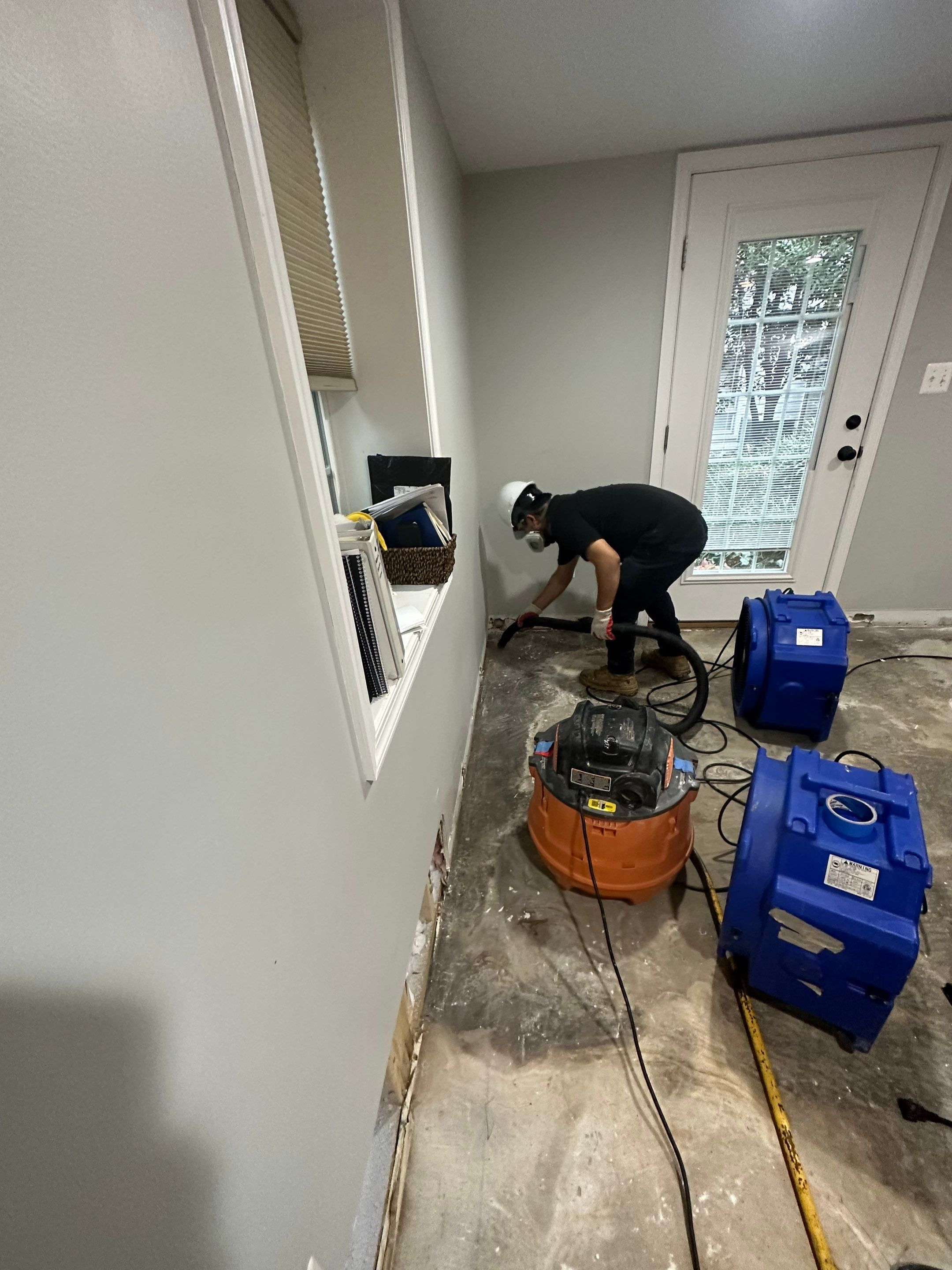 Multiple air movers and dehumidifiers operating to accelerate evaporation and dry structural materials in water-damaged space.