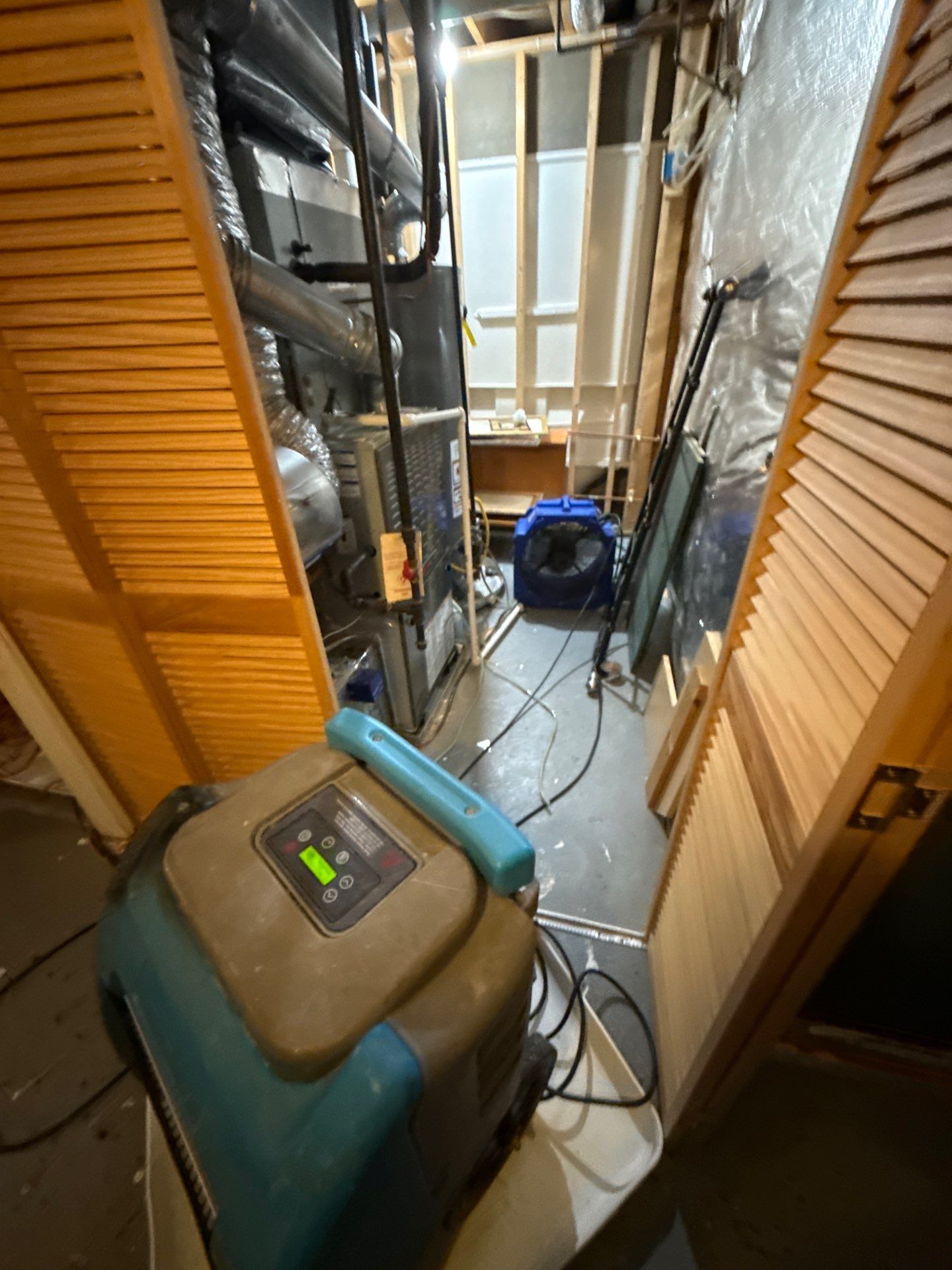 Standing water extraction underway in Woodbridge water damage restoration, wet flooring and lower wall cavity visible.