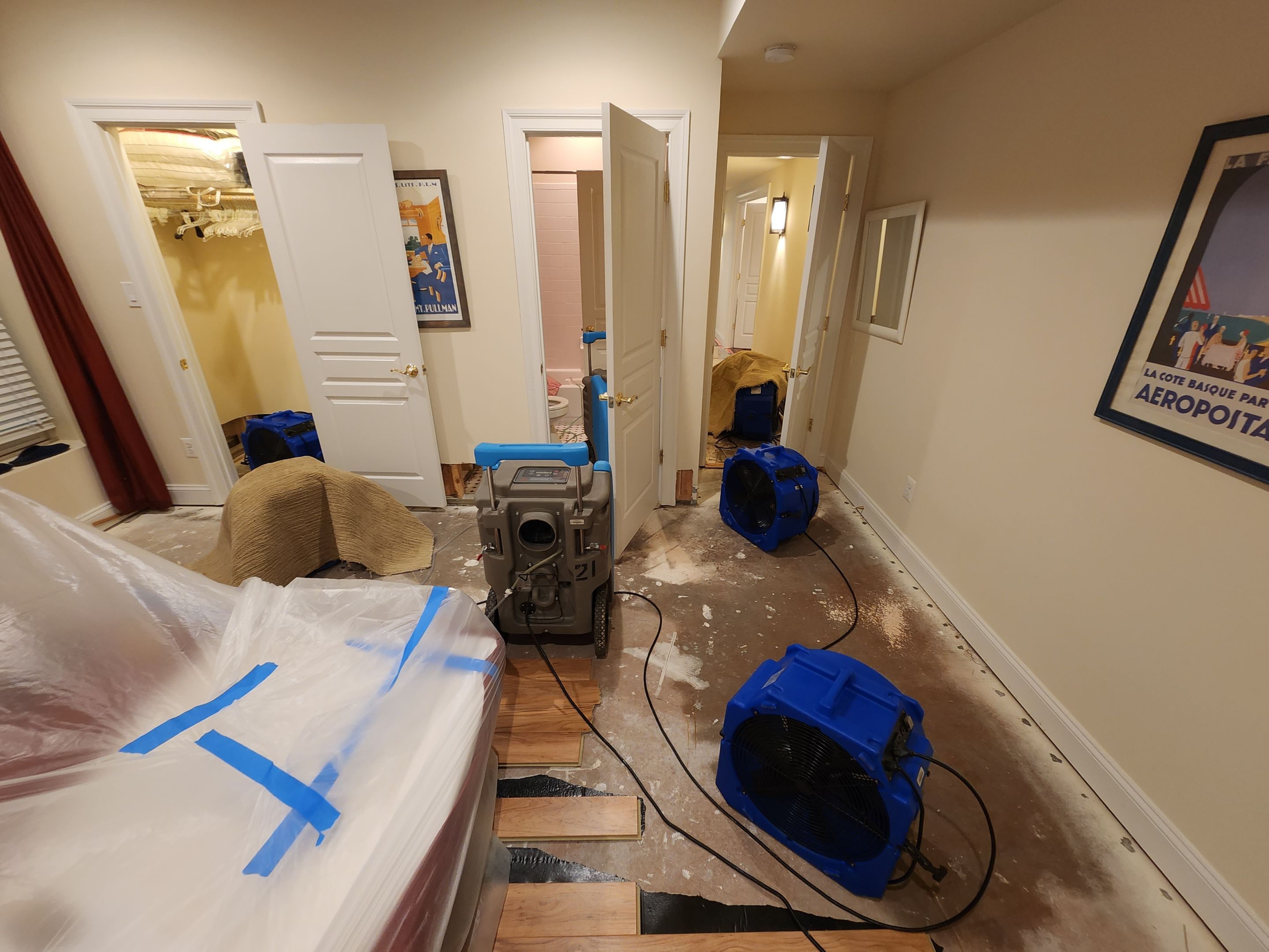 Standing water extraction underway in Leesburg water damage restoration, wet flooring and structural materials visible.