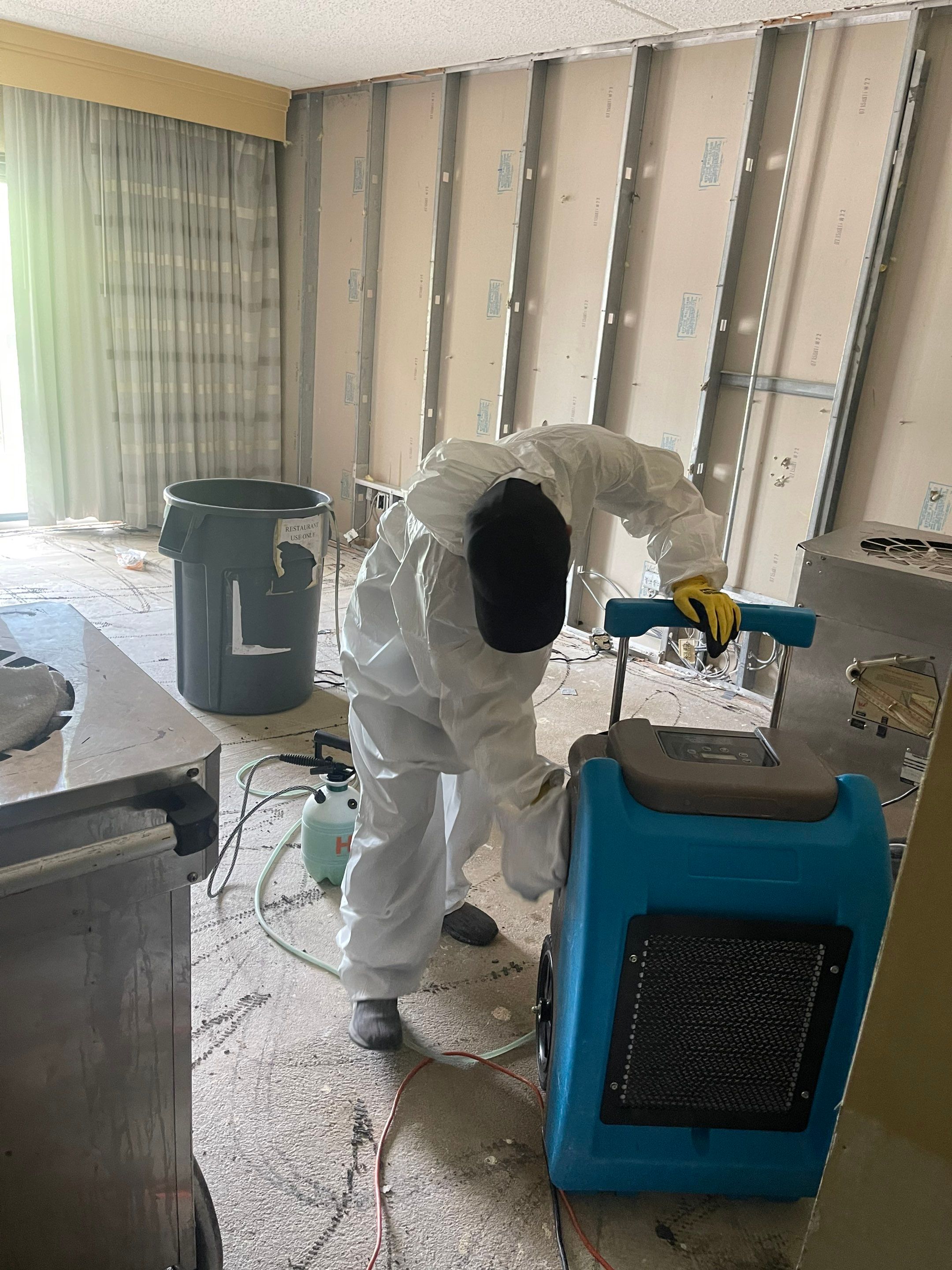 Water damage restoration in Manassas: dehumidifier and drying equipment positioned in affected interior space.