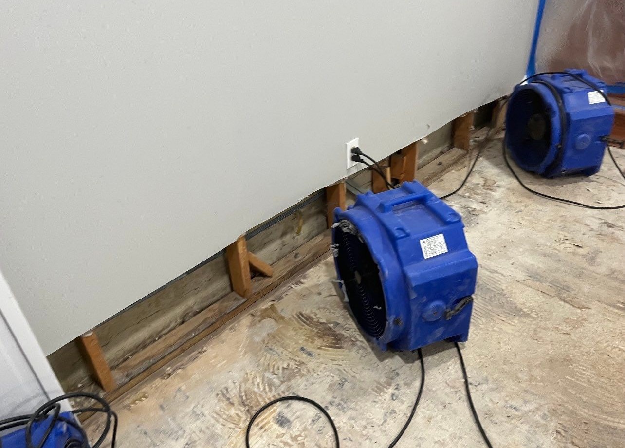 Water-damaged carpet and flooring in Arlington home with dehumidification equipment positioned for structural drying.