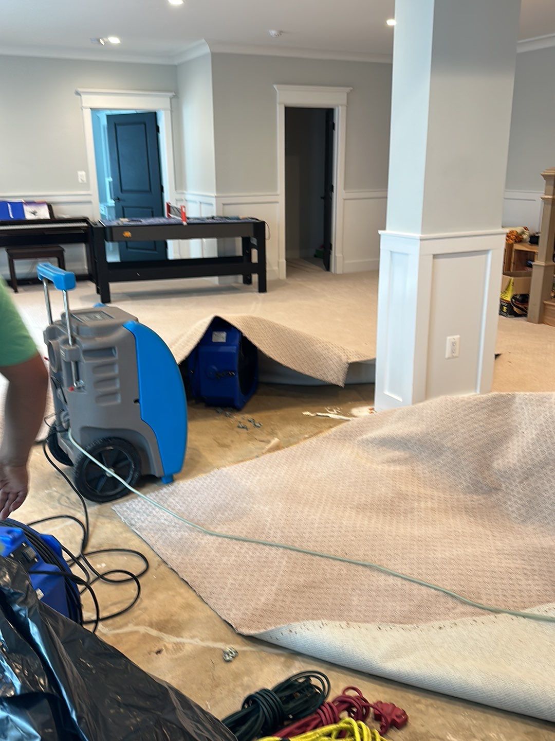 Carpet removal and subfloor exposure mid-restoration, showing structural drying setup in McLean residence.