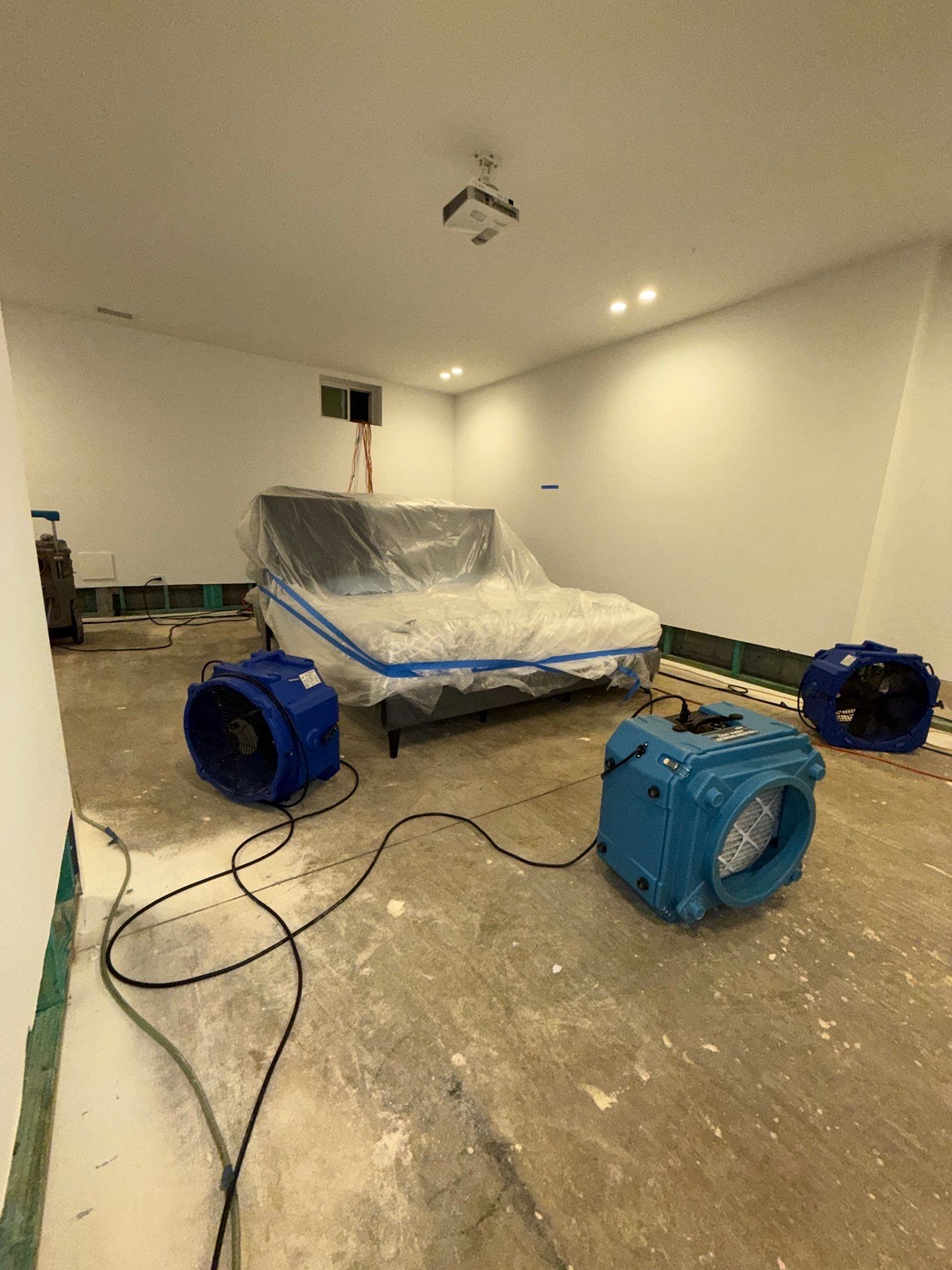 Water damage restoration in Ashburn showing initial structural drying setup with dehumidifiers and air movers positioned throughout affected room.