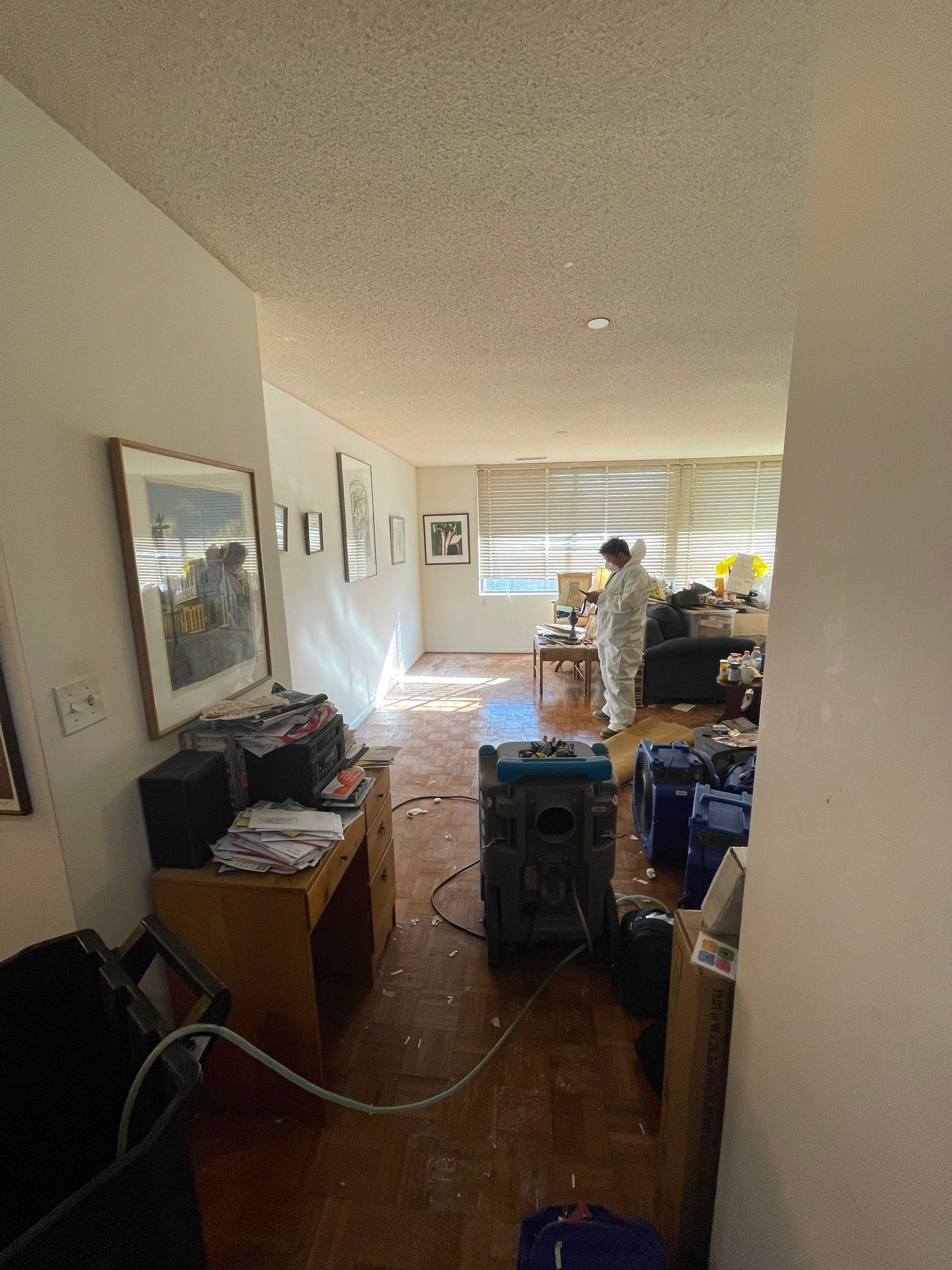 Structural drying in progress with dehumidifiers and air movers positioned throughout affected areas.