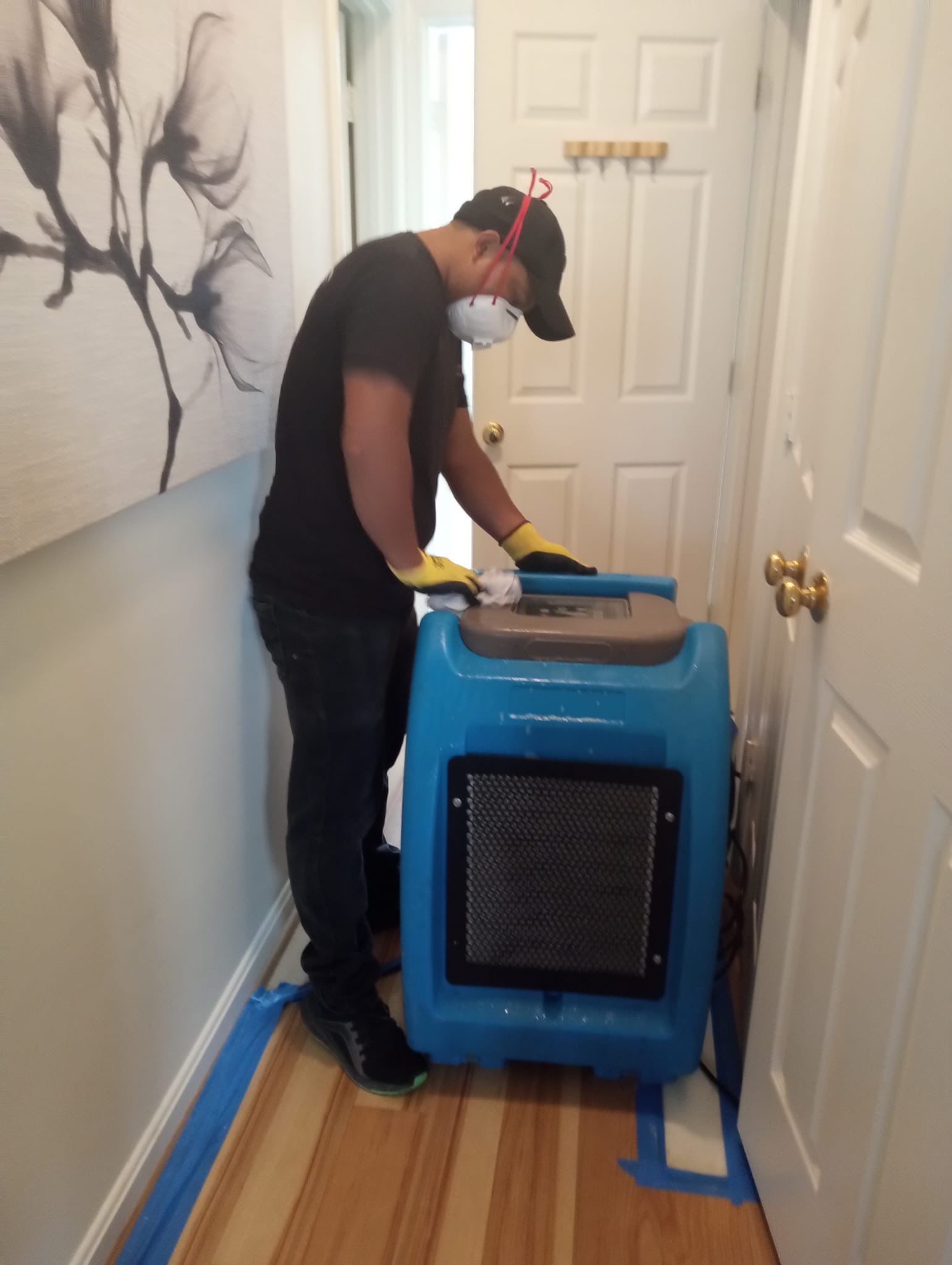 Mid-stage water damage restoration showing continued dehumidification and moisture extraction from affected ceiling area.