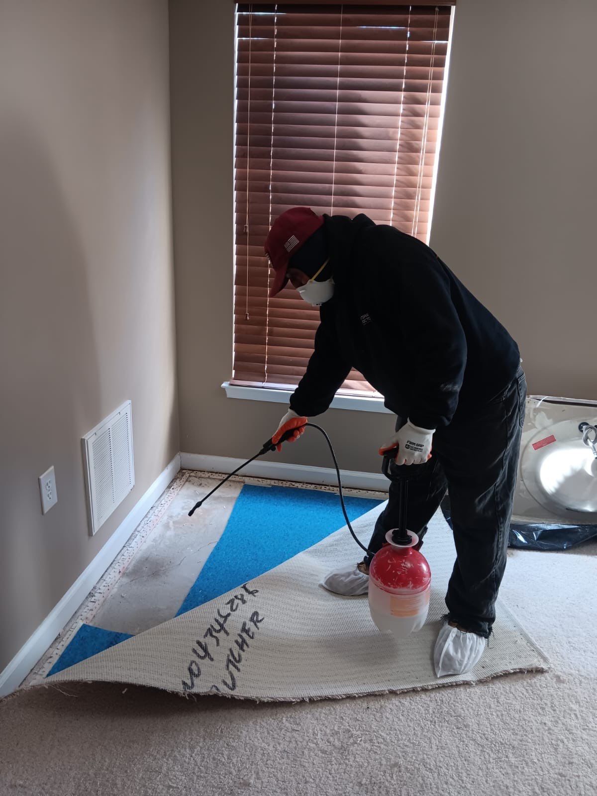 Flooring and carpet removal underway, exposing substructure for assessment and drying before baseboard replacement.