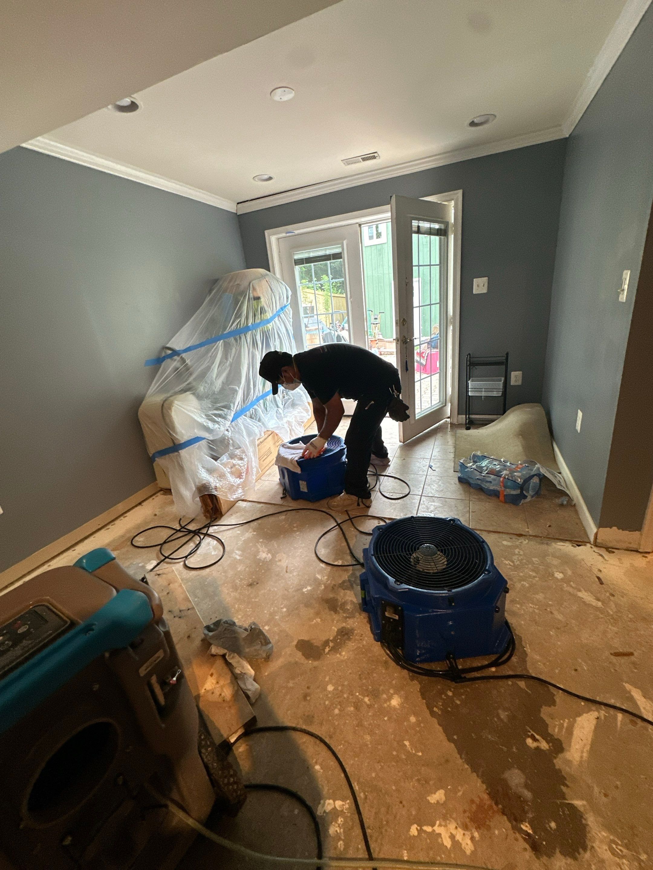 Dehumidifier and drying equipment positioned in water-damaged room during initial assessment and setup in Annandale.