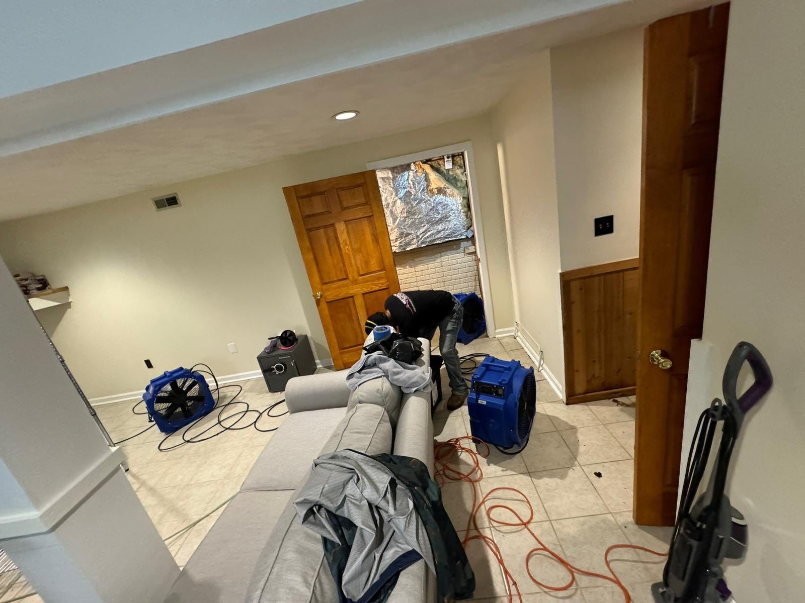 Structural drying in progress with dehumidifiers and air movers positioned throughout affected areas.