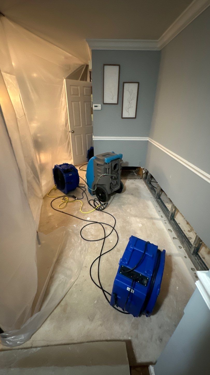 Water-damaged carpet and flooring in Manassas home with dehumidification equipment positioned for structural drying.