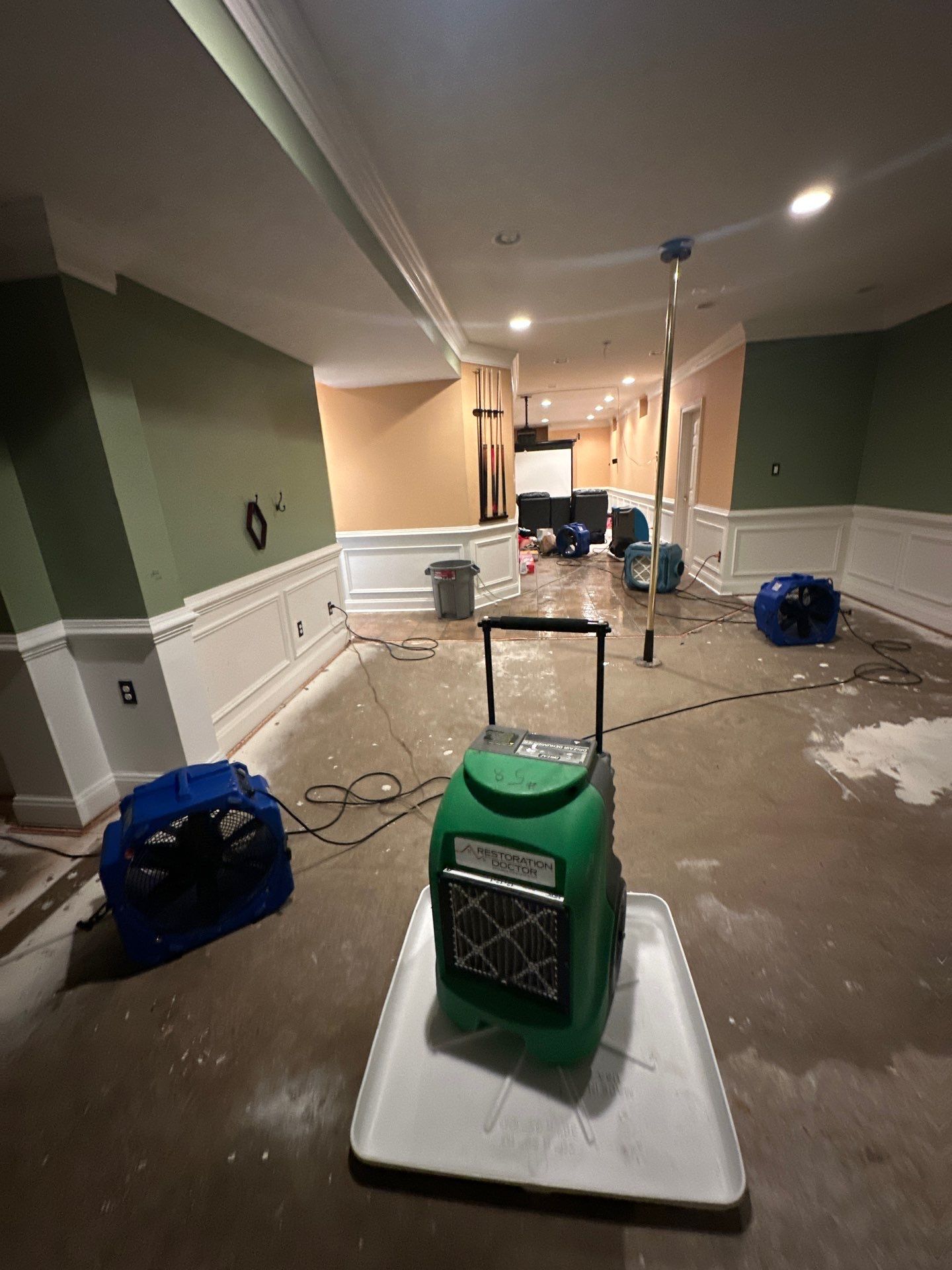 Wet carpet and padding removal in progress, exposing subflooring for assessment and continued drying operations.