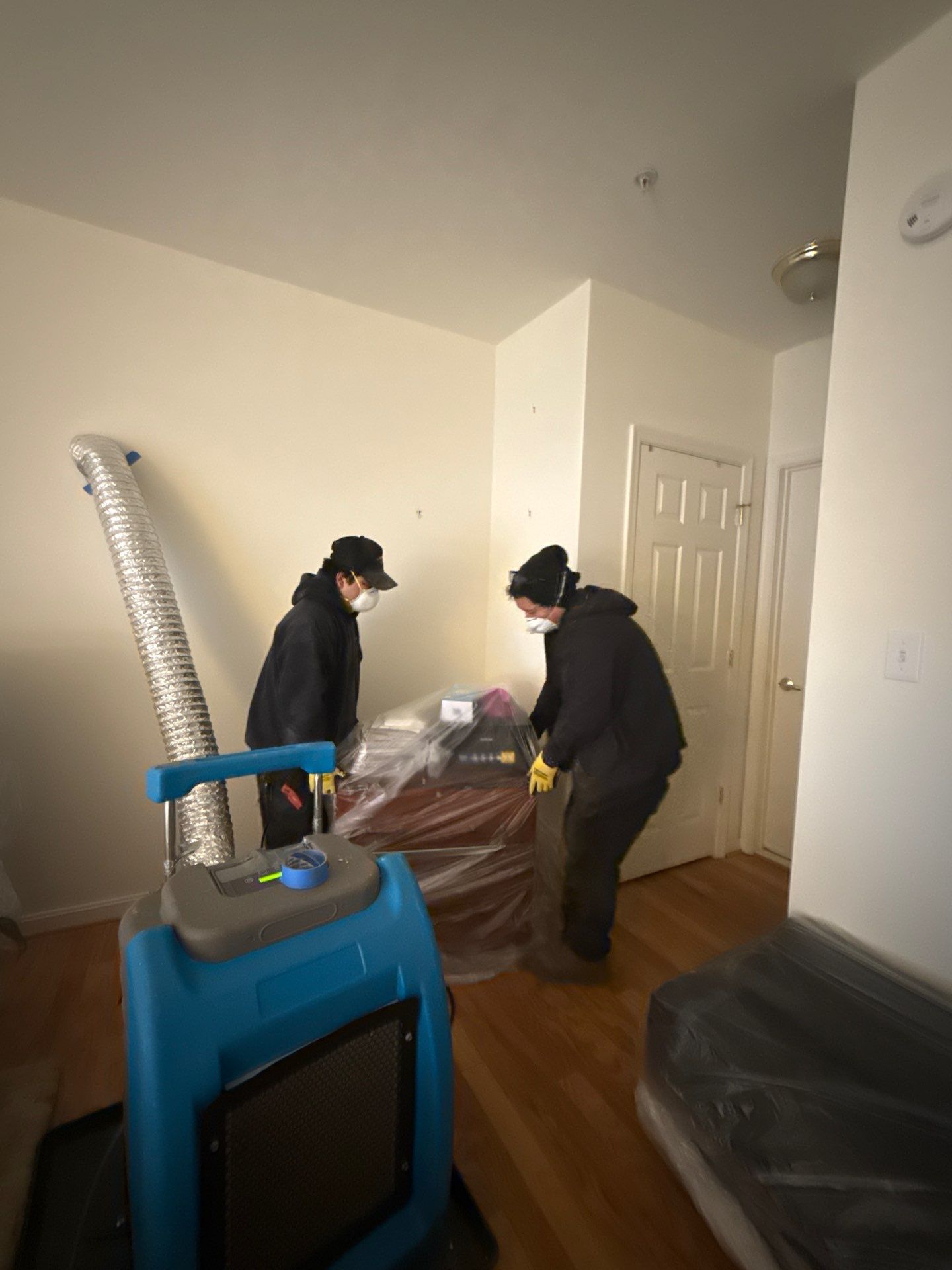 Standing water extraction underway in Alexandria water damage restoration, structural materials exposed.