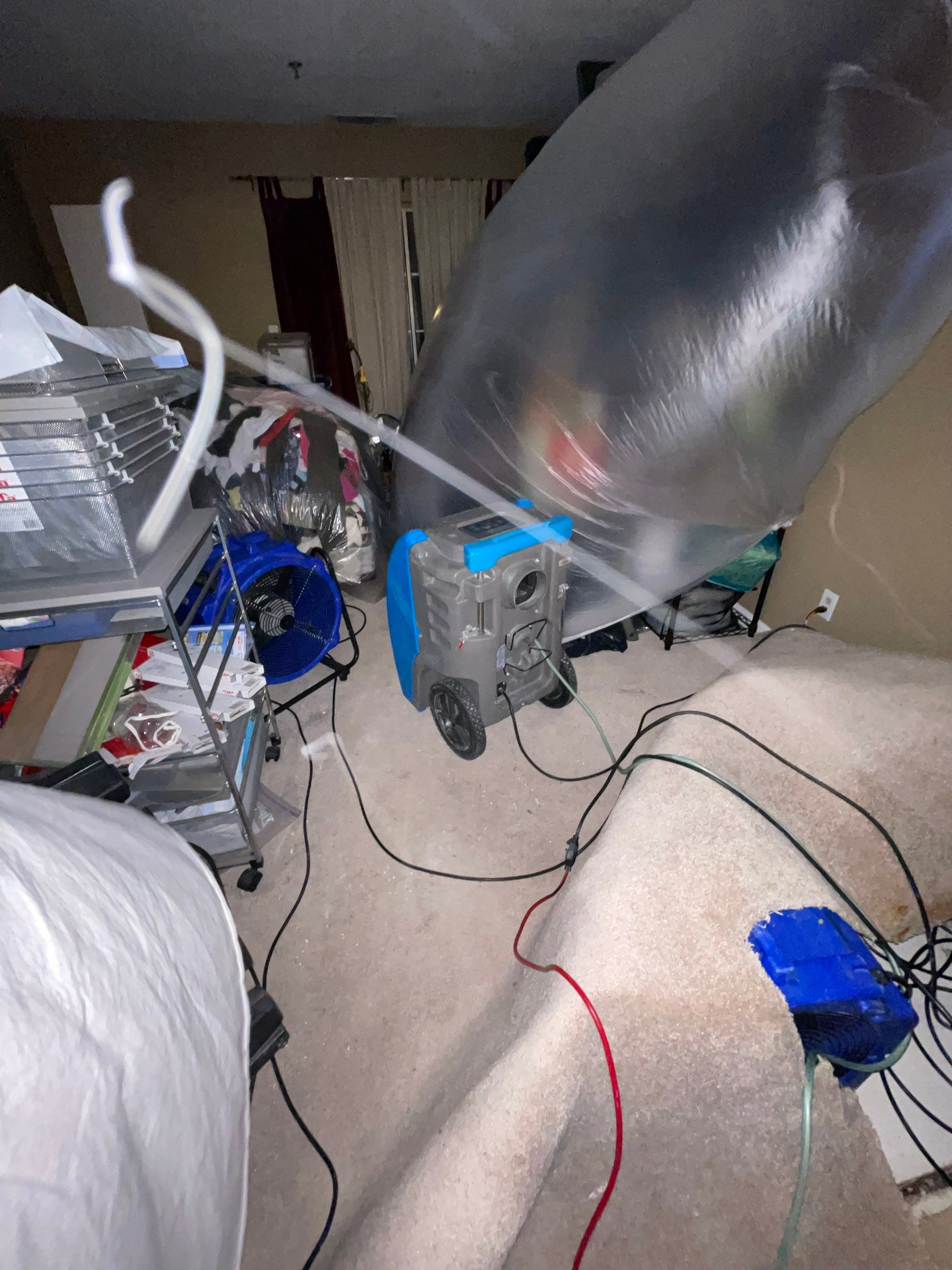 Mid-stage water damage restoration showing active dehumidification within containment area.