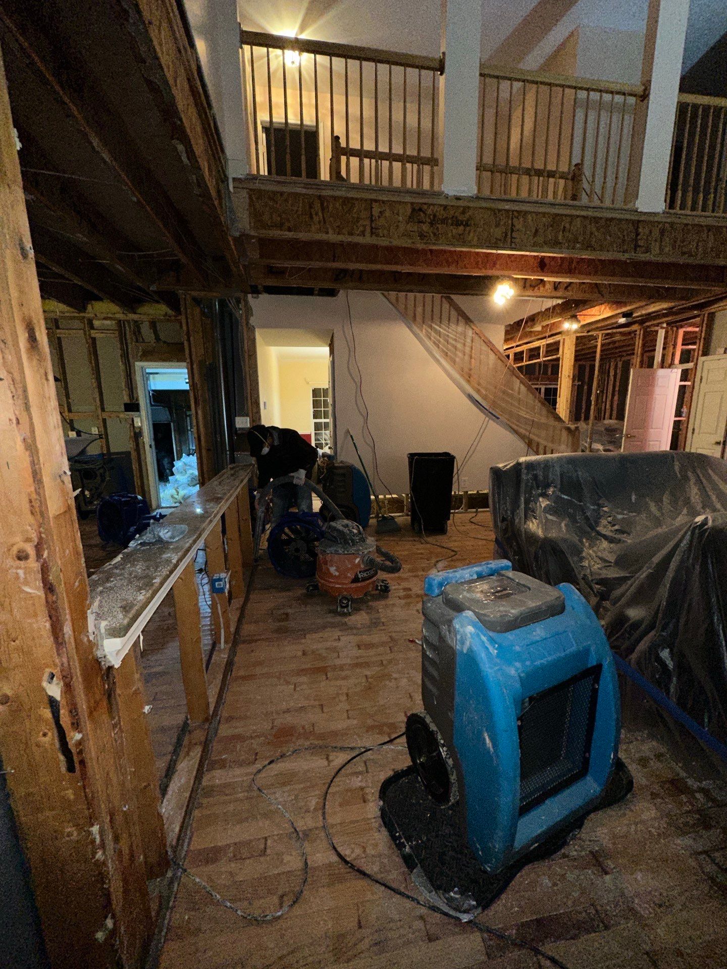 Mid-stage water restoration showing structural drying setup with dehumidifiers and air movers addressing ceiling and floor moisture.