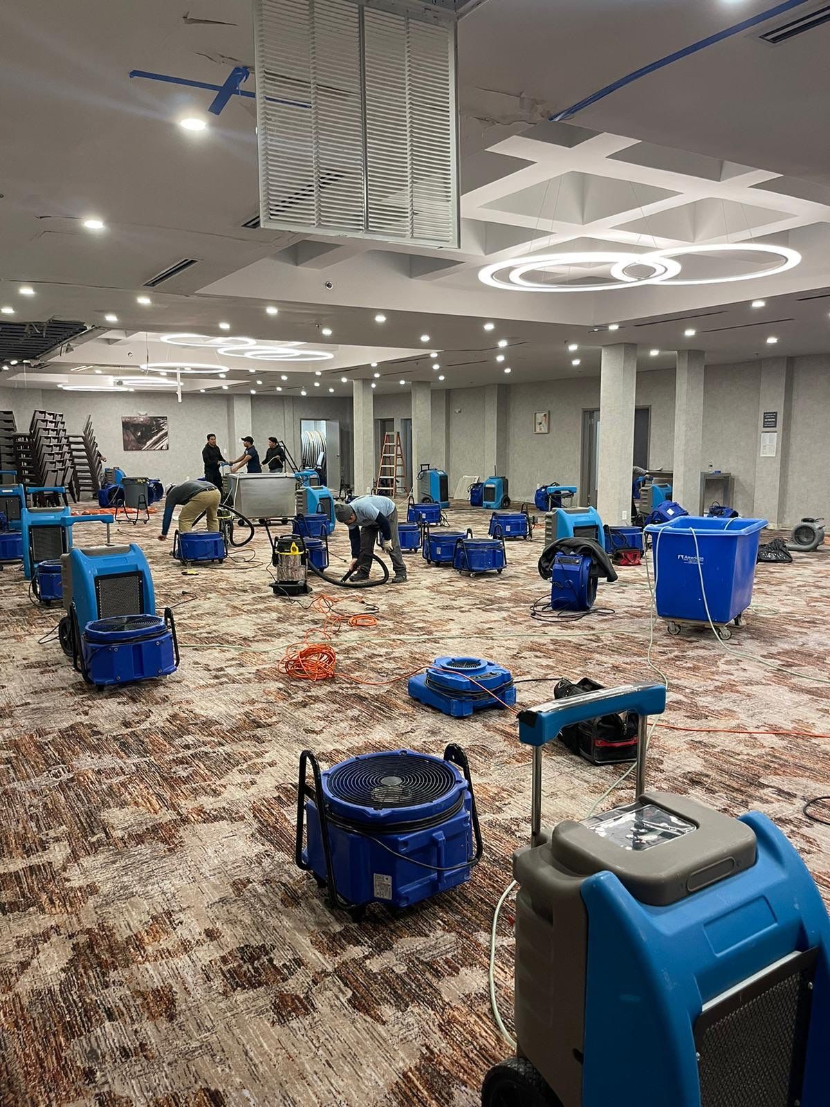 Standing water extraction underway in Falls Church water damage restoration, wet flooring visible.