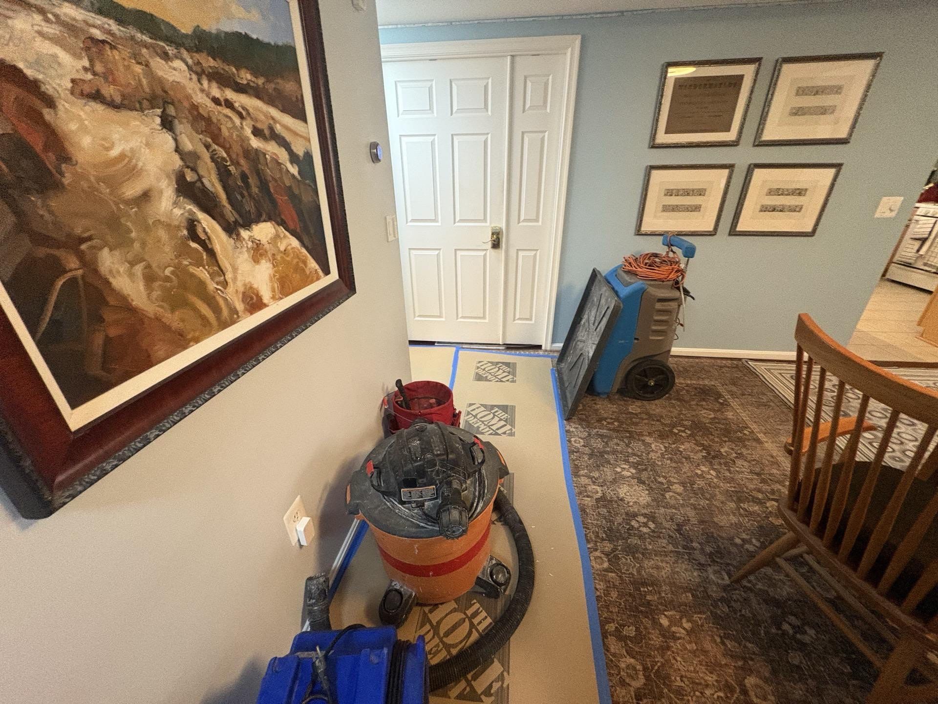 Mid-stage water restoration in Arlington showing dehumidification setup and flooring assessment during active drying phase.