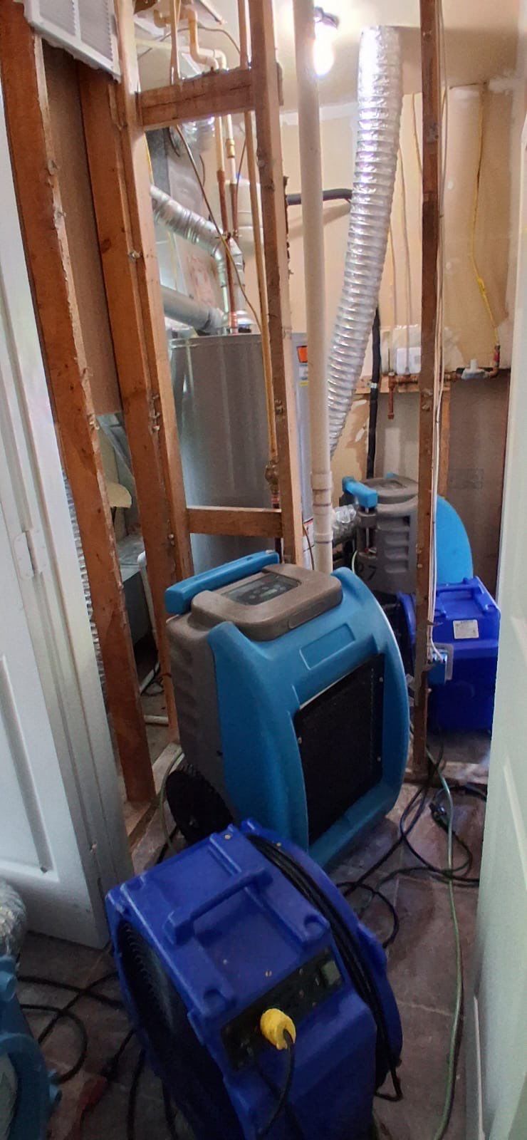 Technician positioning extraction and dehumidification equipment to address standing water from the tank failure.