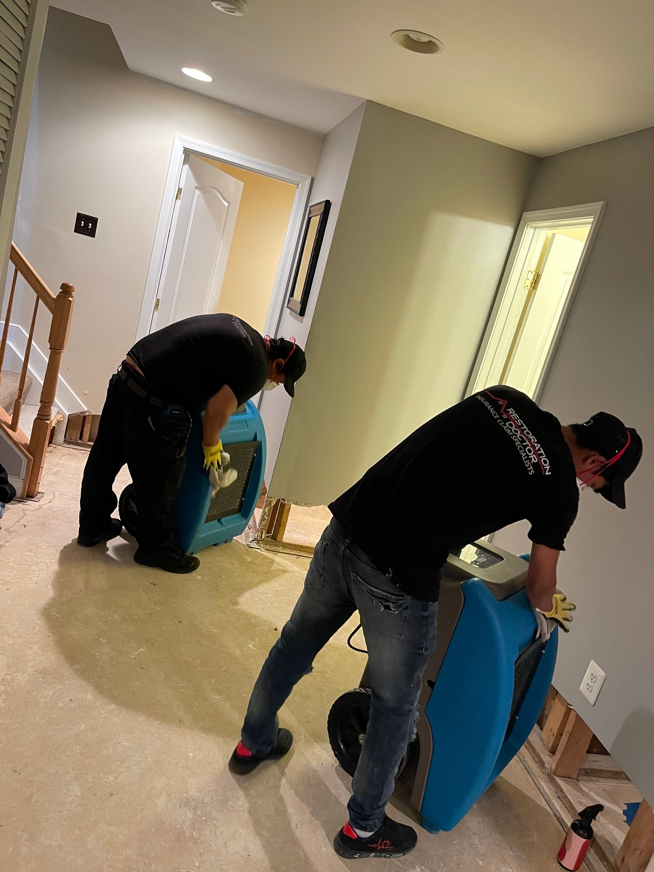 Standing water extraction underway in Alexandria water damage restoration, wet flooring visible.