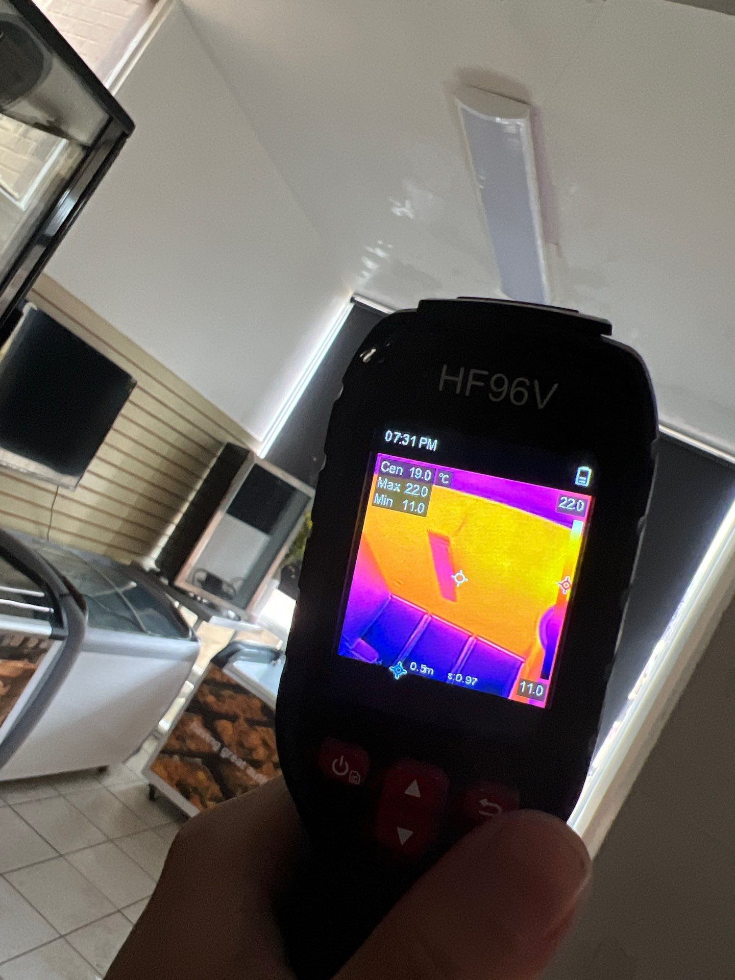 Technician using thermal imaging to locate hidden moisture behind ceiling materials.