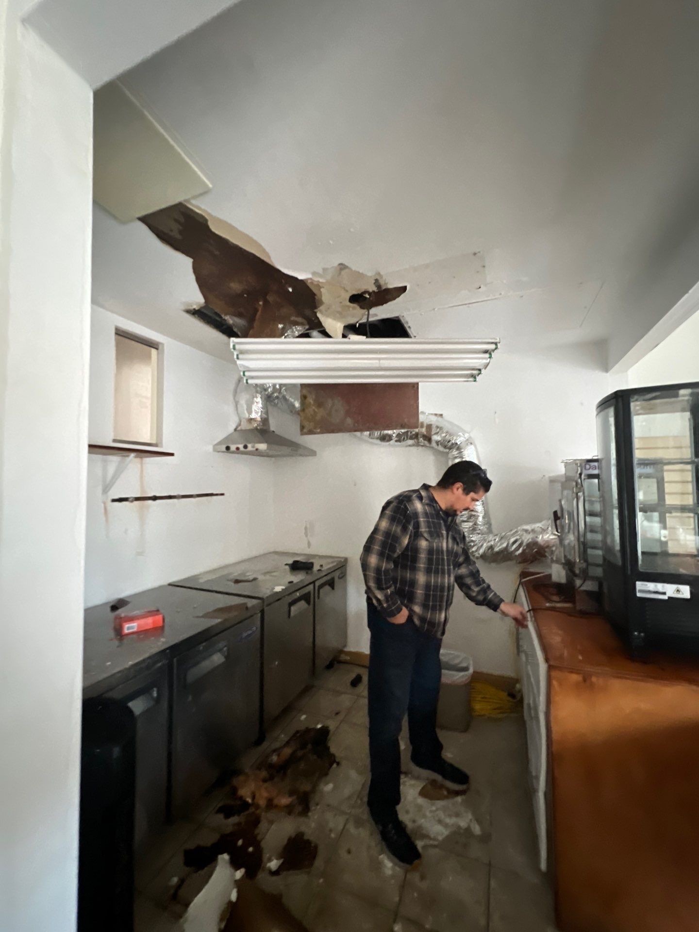 Removal of water-damaged drywall and insulation from ceiling cavity.