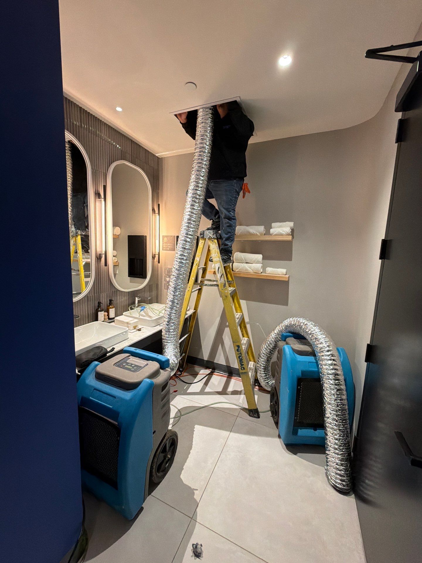 Dehumidifiers and air movers deployed for moisture removal in water-damaged interior.