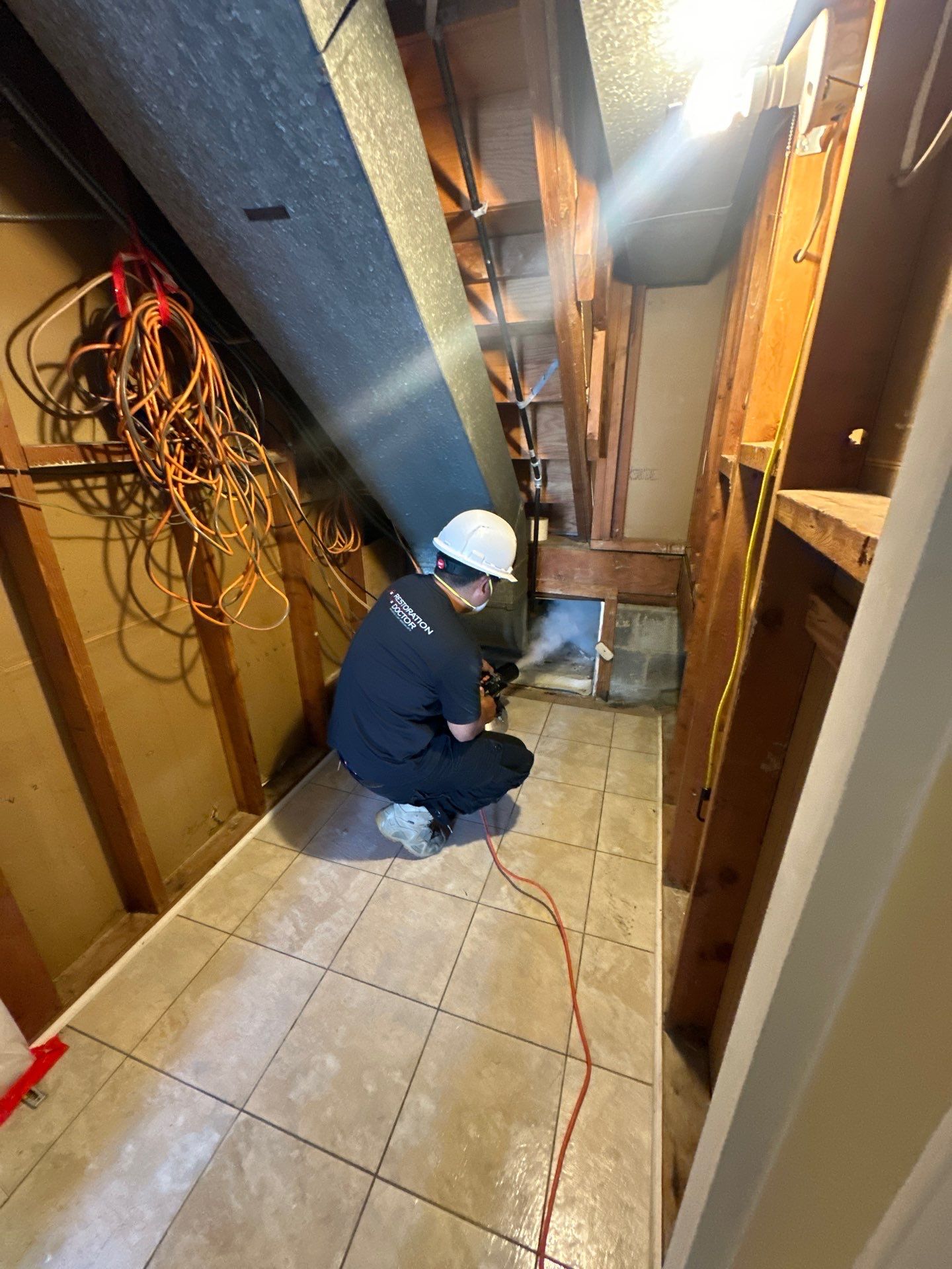 Water damage restoration in Alexandria: dehumidifier and drying equipment positioned in affected room during initial assessment and setup.