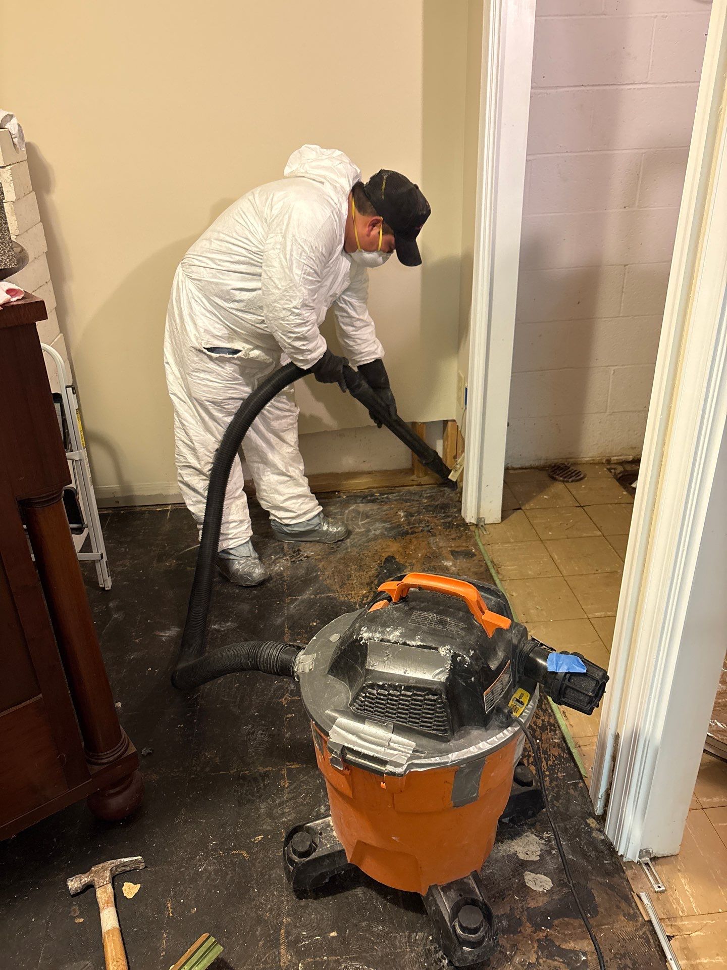 Standing water extraction underway in Falls Church water damage restoration, wet flooring and wall base visible.