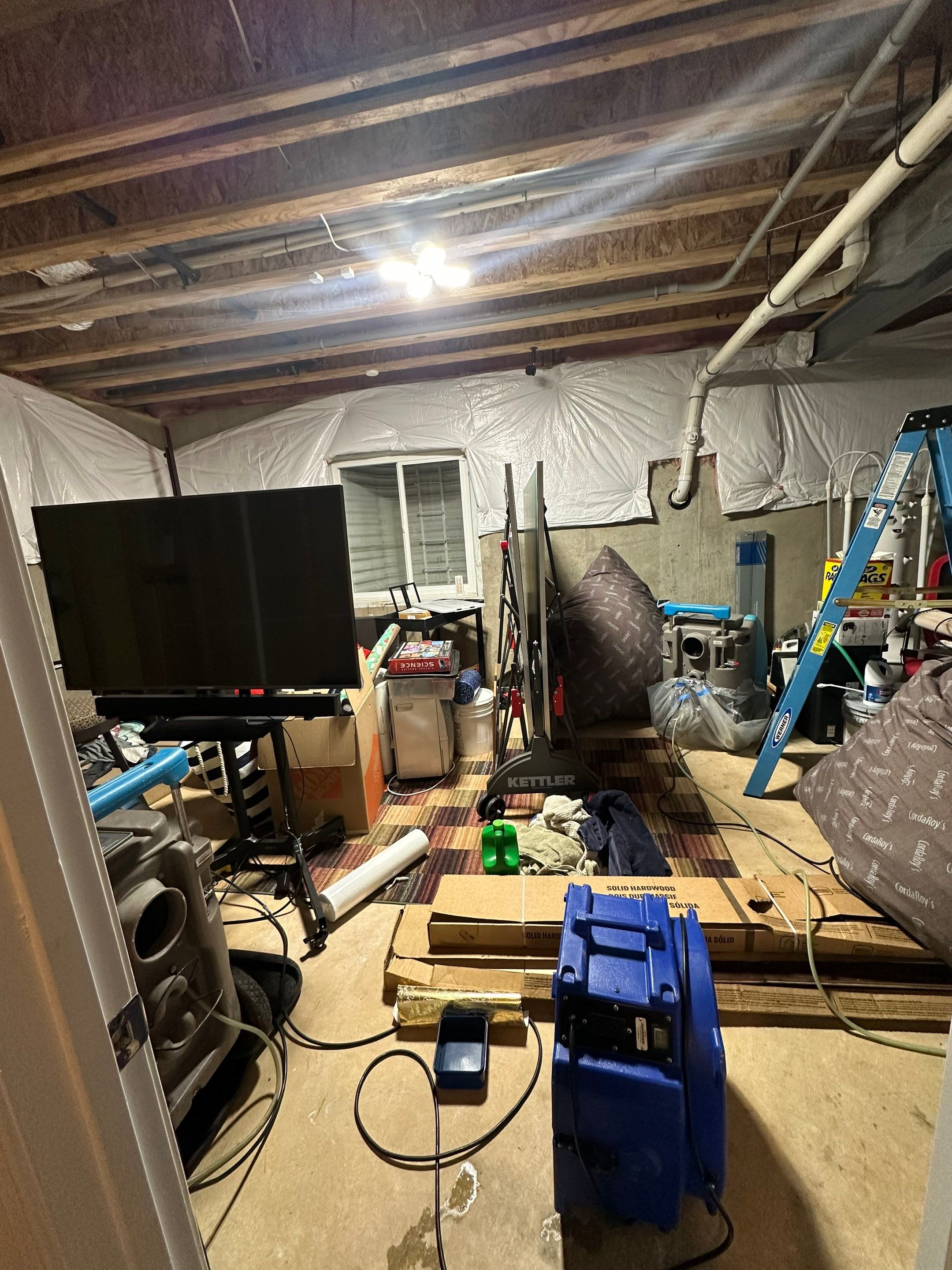 Mid-stage drying setup showing dehumidifiers and air movers directing airflow through affected structural areas.