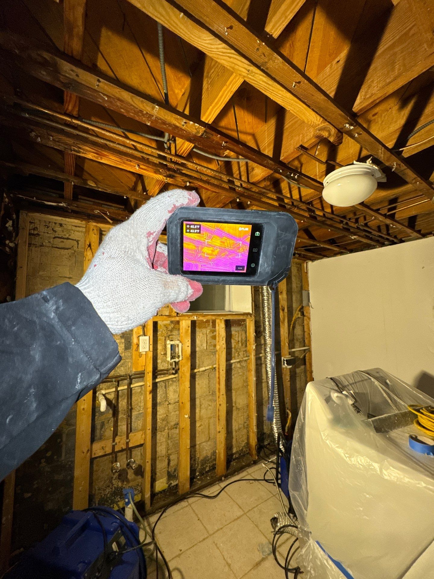 Moisture inspection equipment positioned to map affected drywall and framing in damaged ceiling area.